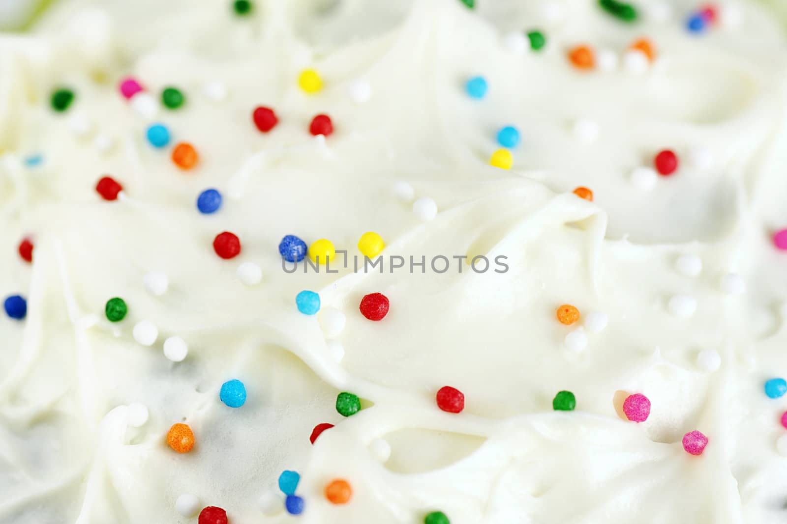 Great appetizing background of cream cheese cake frosting or icing with colorful sugar candy.