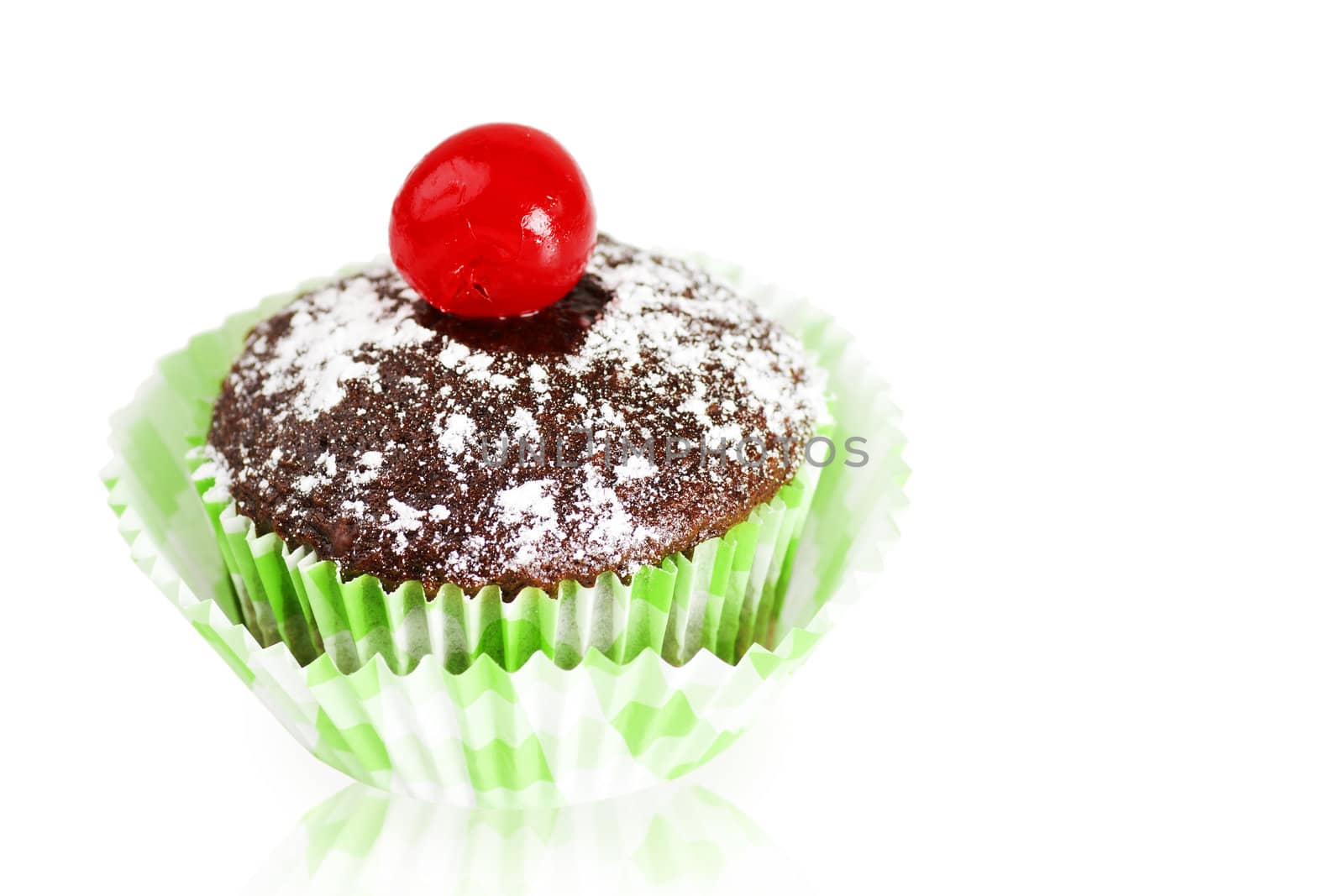 Delicious chocolate cupcakes topped with powdered sugar and maraschino cherry over white reflective background as copy space.