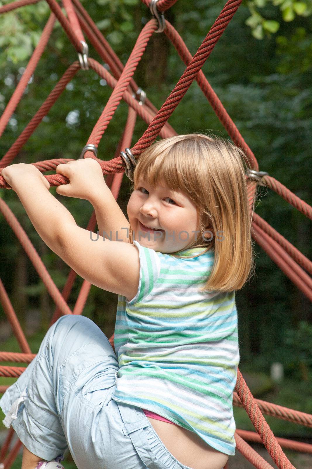 small blonde girl climbing a rope climbing frame