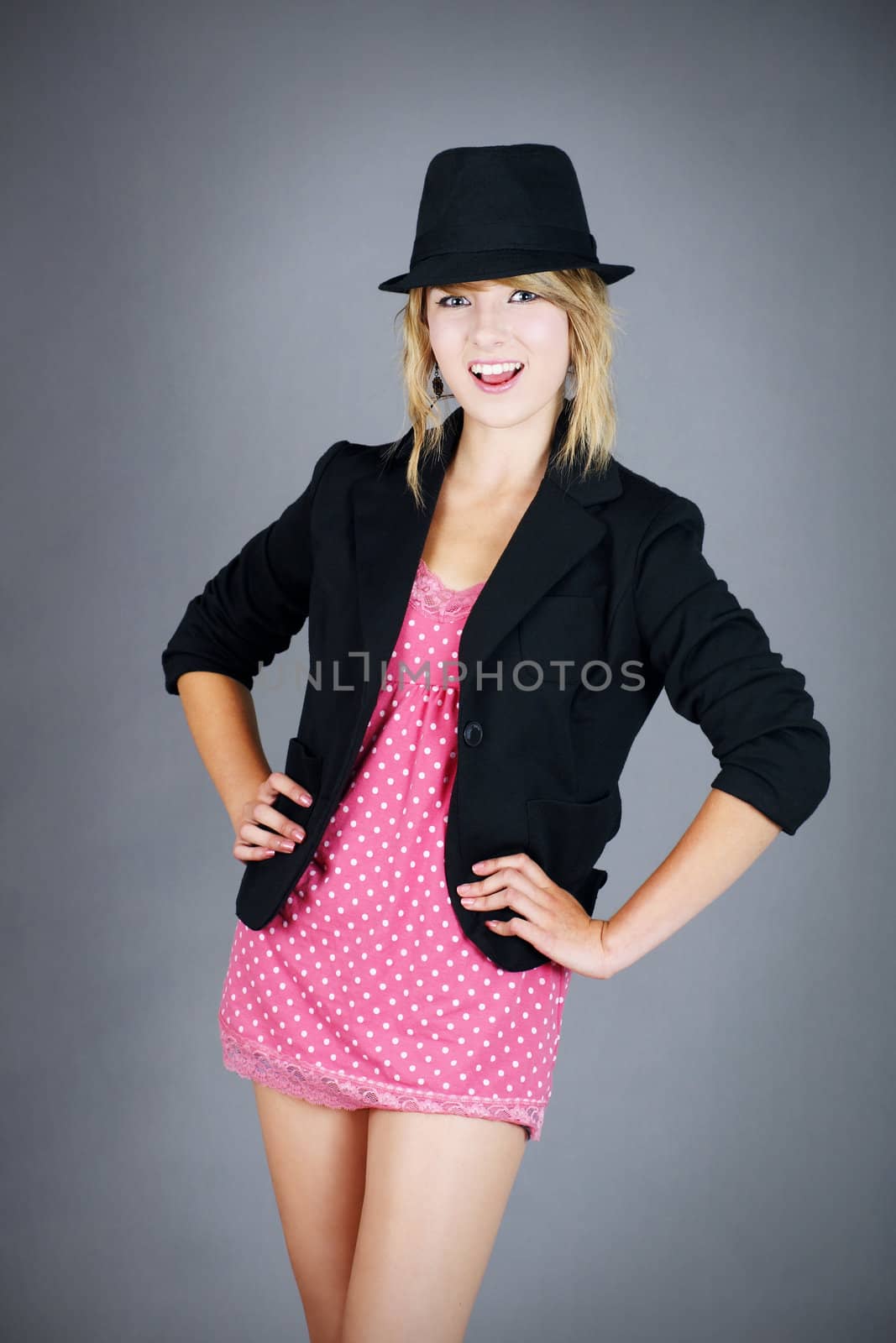 Fun and cute young blond girl burlesque or cabaret dancer ready for the show, studio shot over grey background.