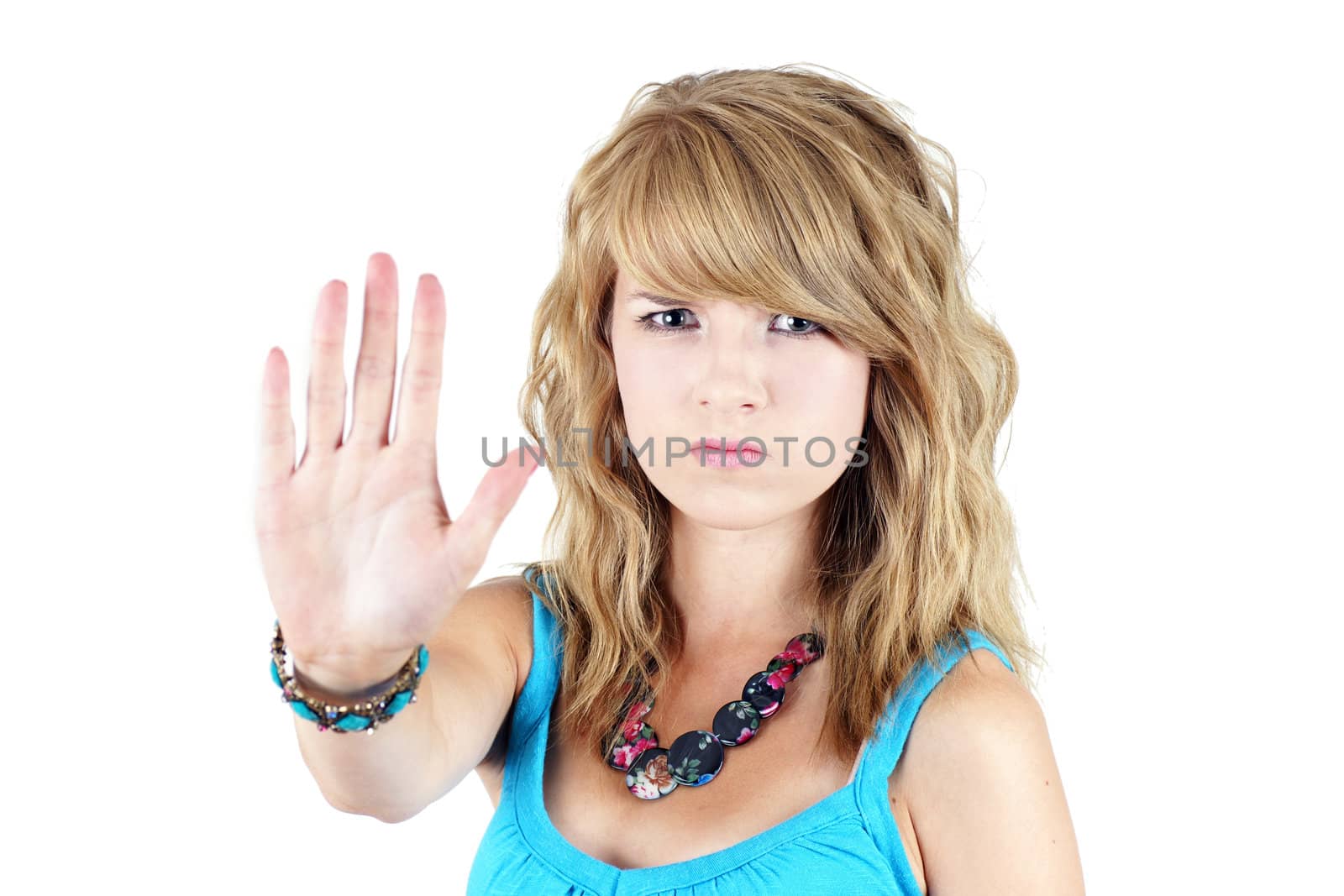 Young blond teenager girl with sad or angry face raising her hand to say NO or STOP, strong concept against drugs, violence, abuse or others: focus on face.
