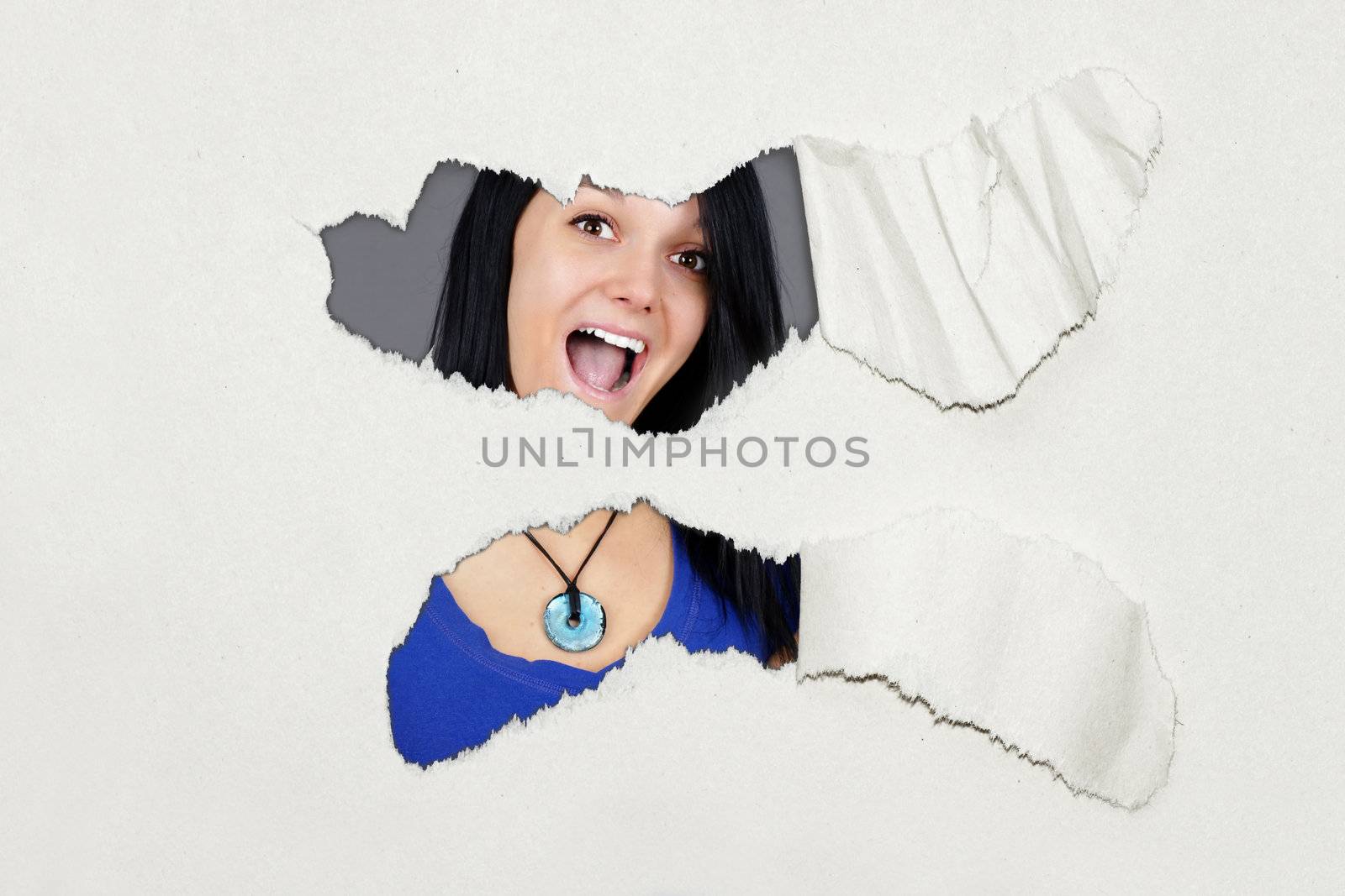 Surprised young woman under ripped paper by Mirage3