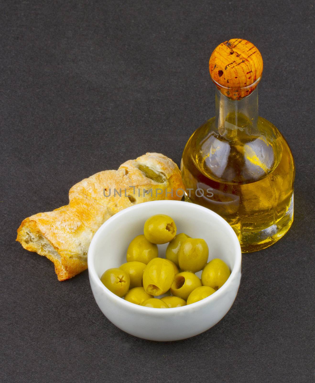 Olives, olive oil and bread with olives over black background