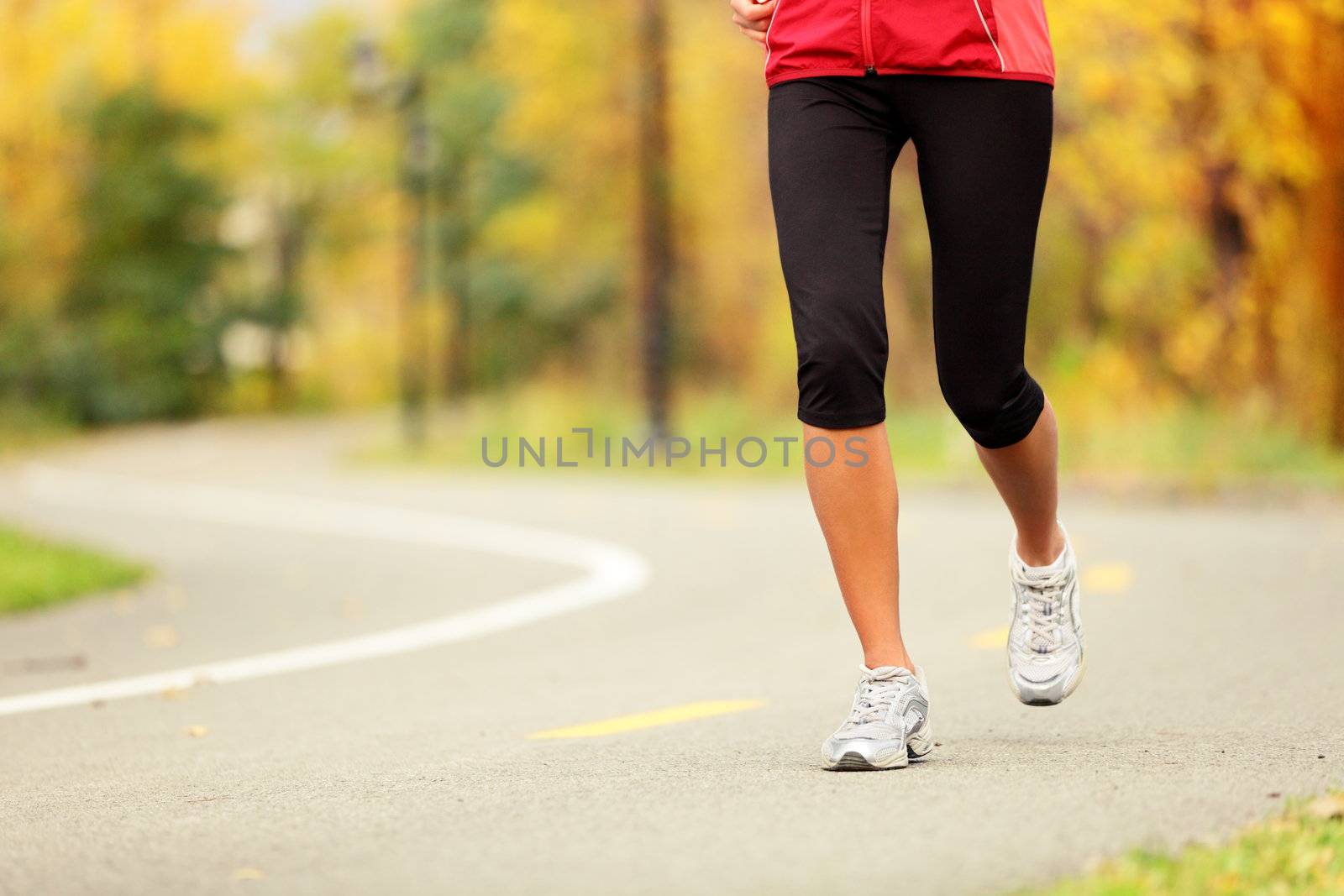 Runner legs and running shoes. Woman jogging in fall colors on forest path.