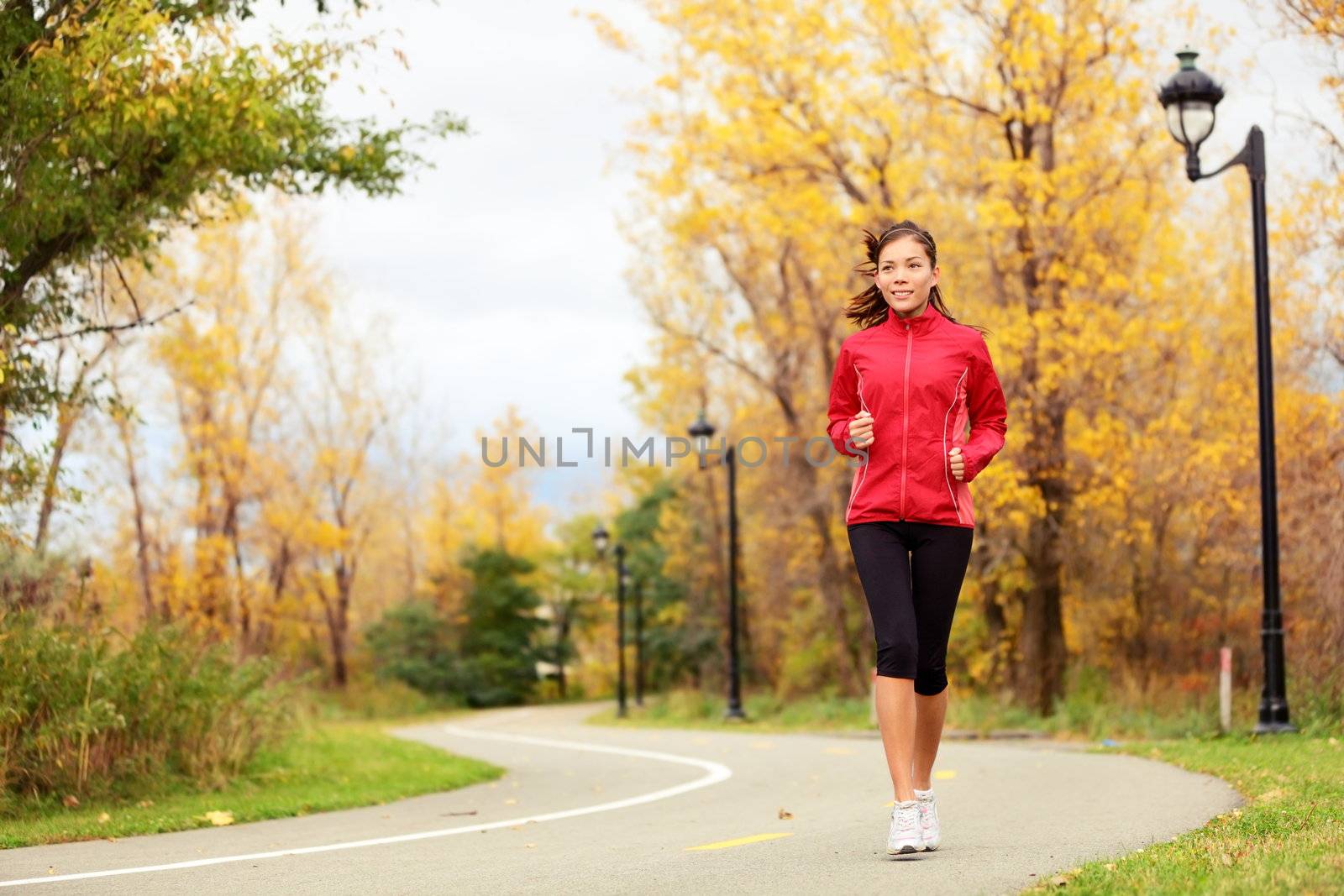 Fall running - woman jogging in autumn in city park.  Female jogger training outside. Beautiful young multi-ethnic woman model in her twenties.