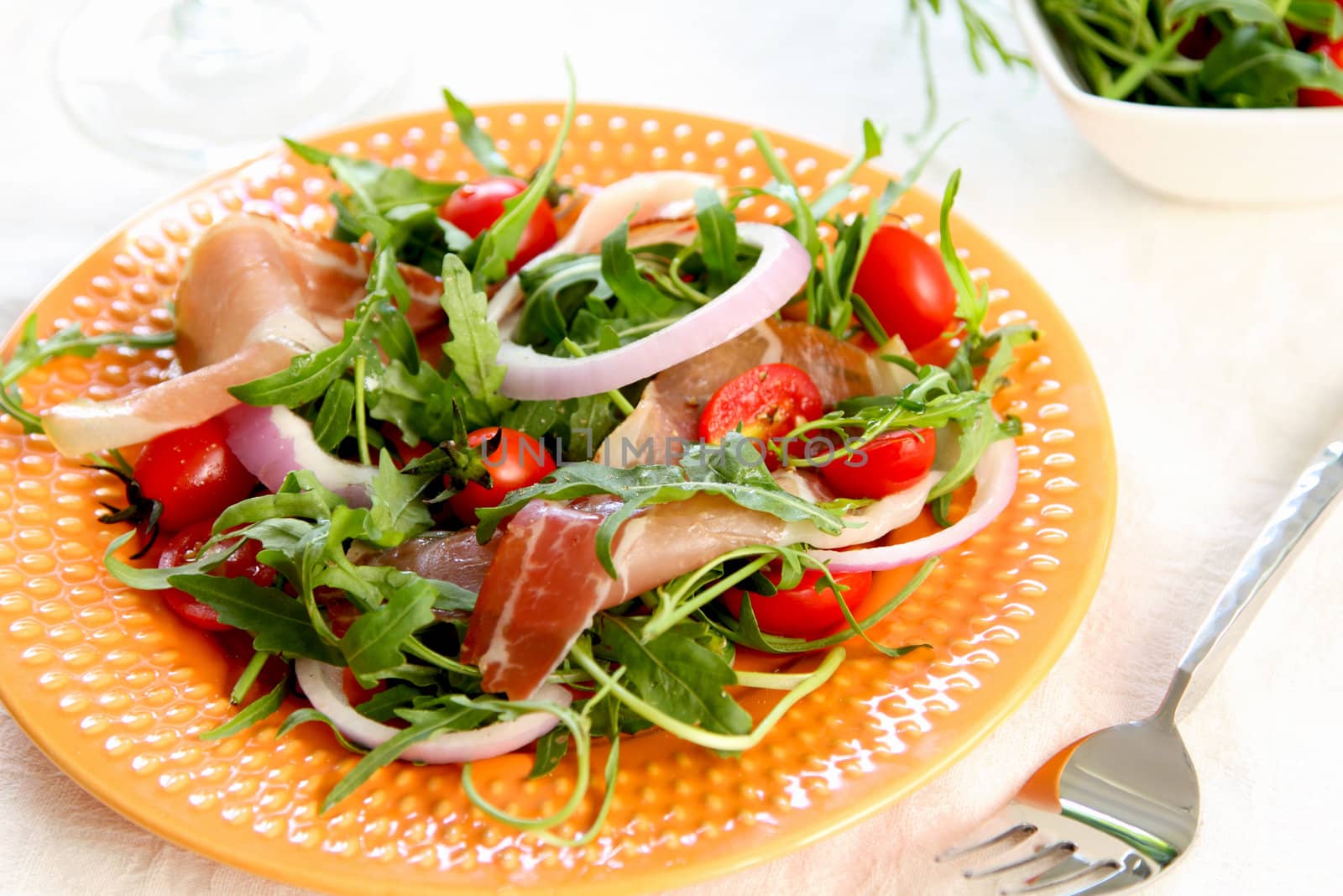 Prosciutto withcherry tomato,and rocket salad on orange dish