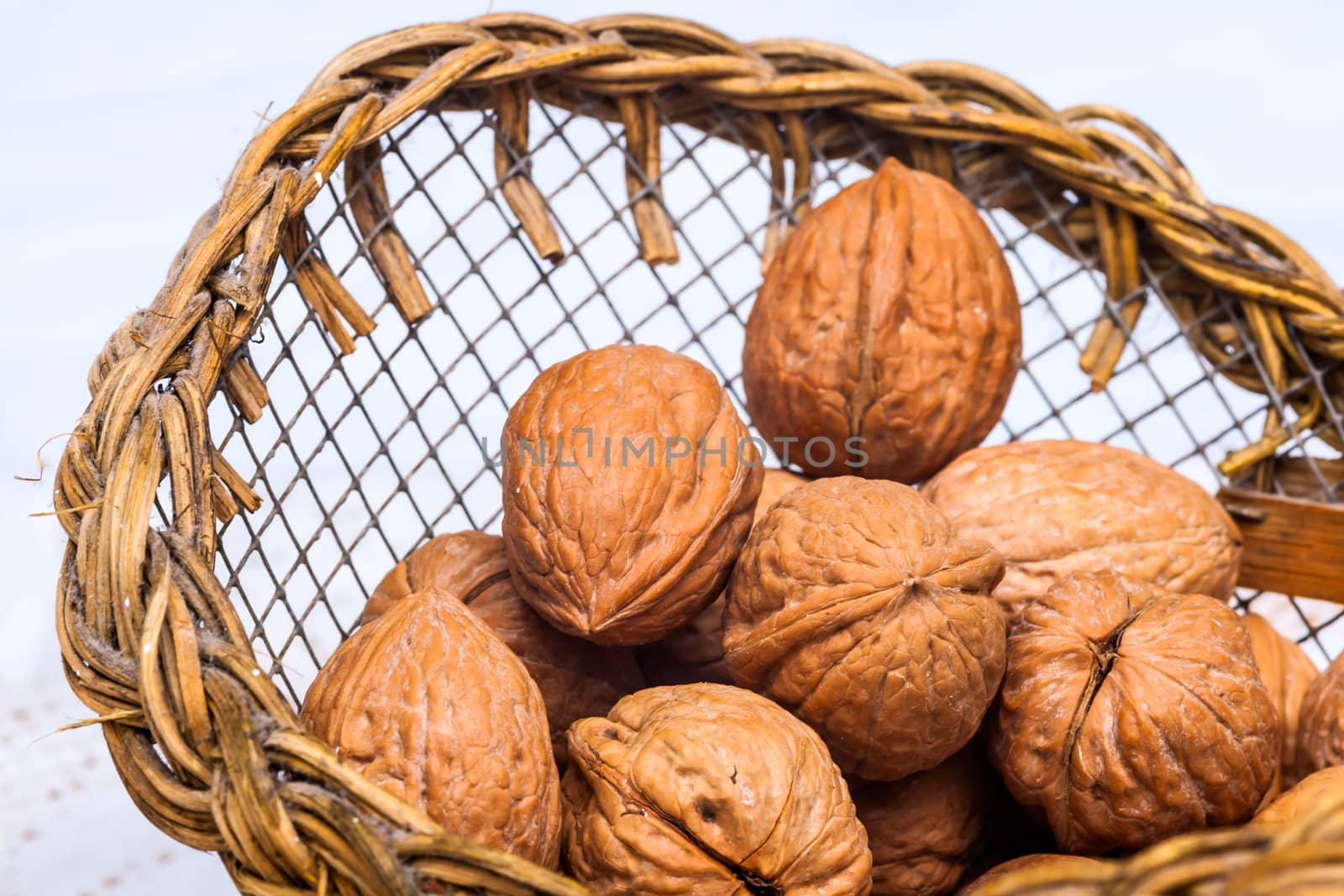 A composition of walnuts on a basket over a white background