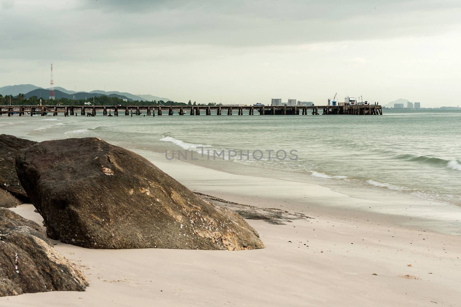 Big stone in sand on beach with jetty by moggara12