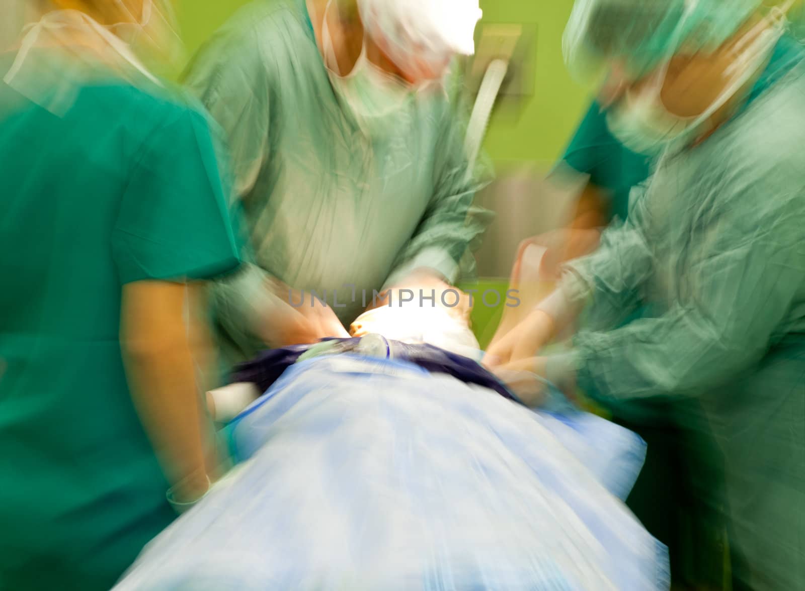 Blurred figures of surgeonts in medical uniforms performing surgery