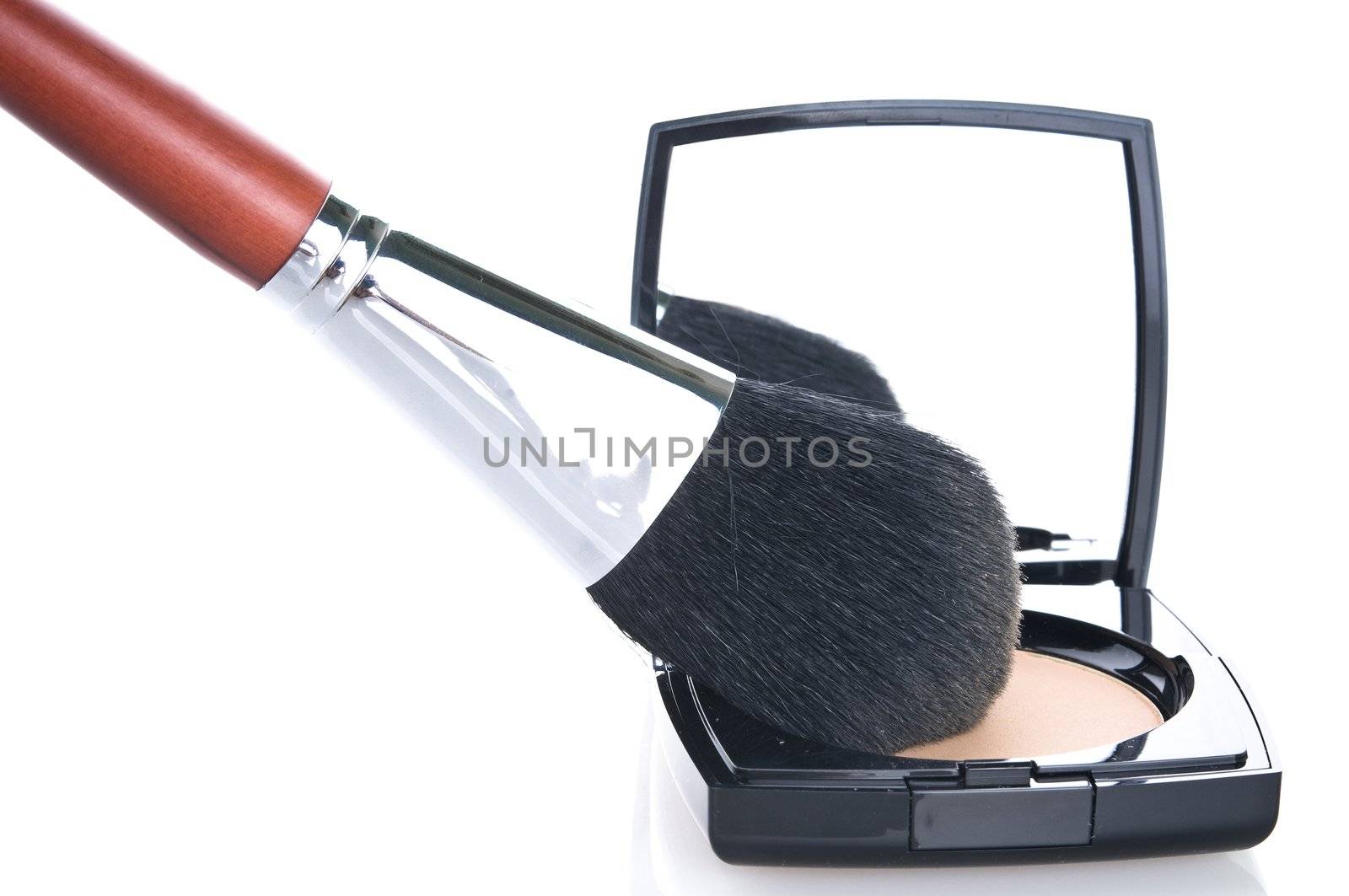 Make-up brush on powder-case with mirror. Selective focus on the brush