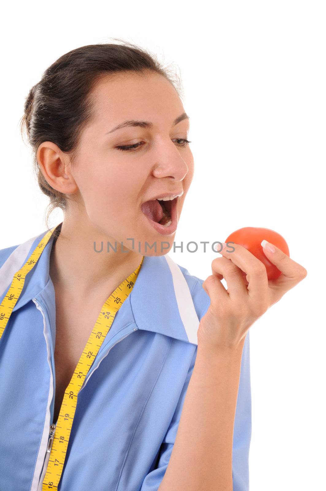 Young woman in blue uniform with measuring type is eating red tomato. Isolated on white background.