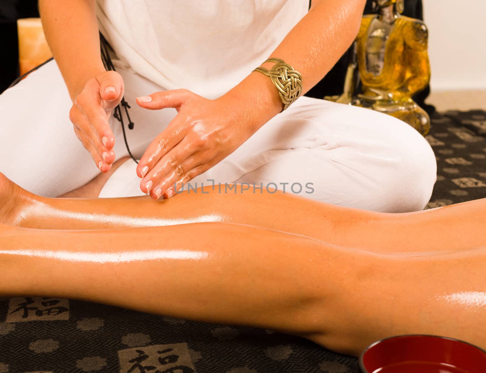 Hands massaging thighs in an oriental setting