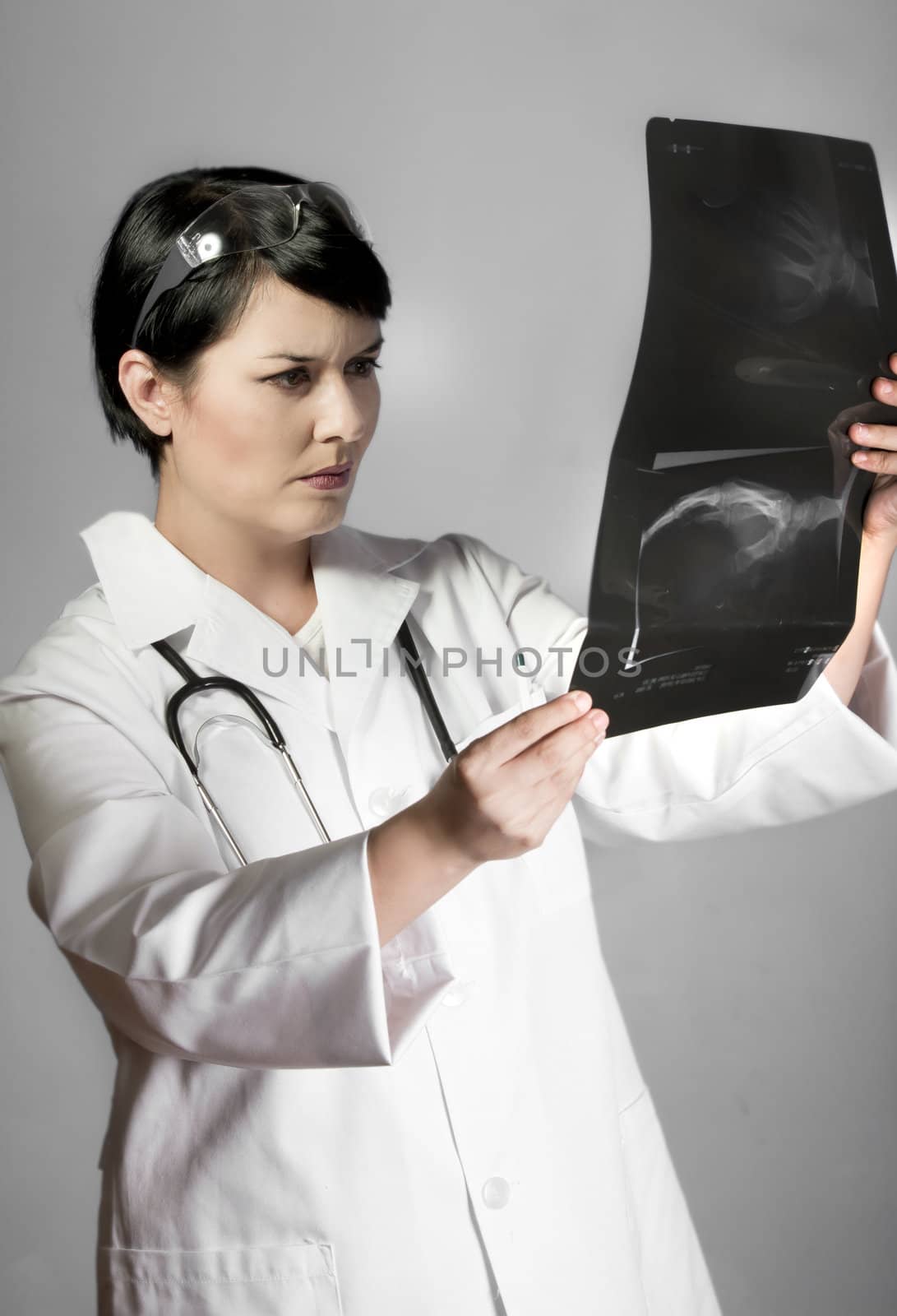 brunette female doctor checking X-Rays over neutral background