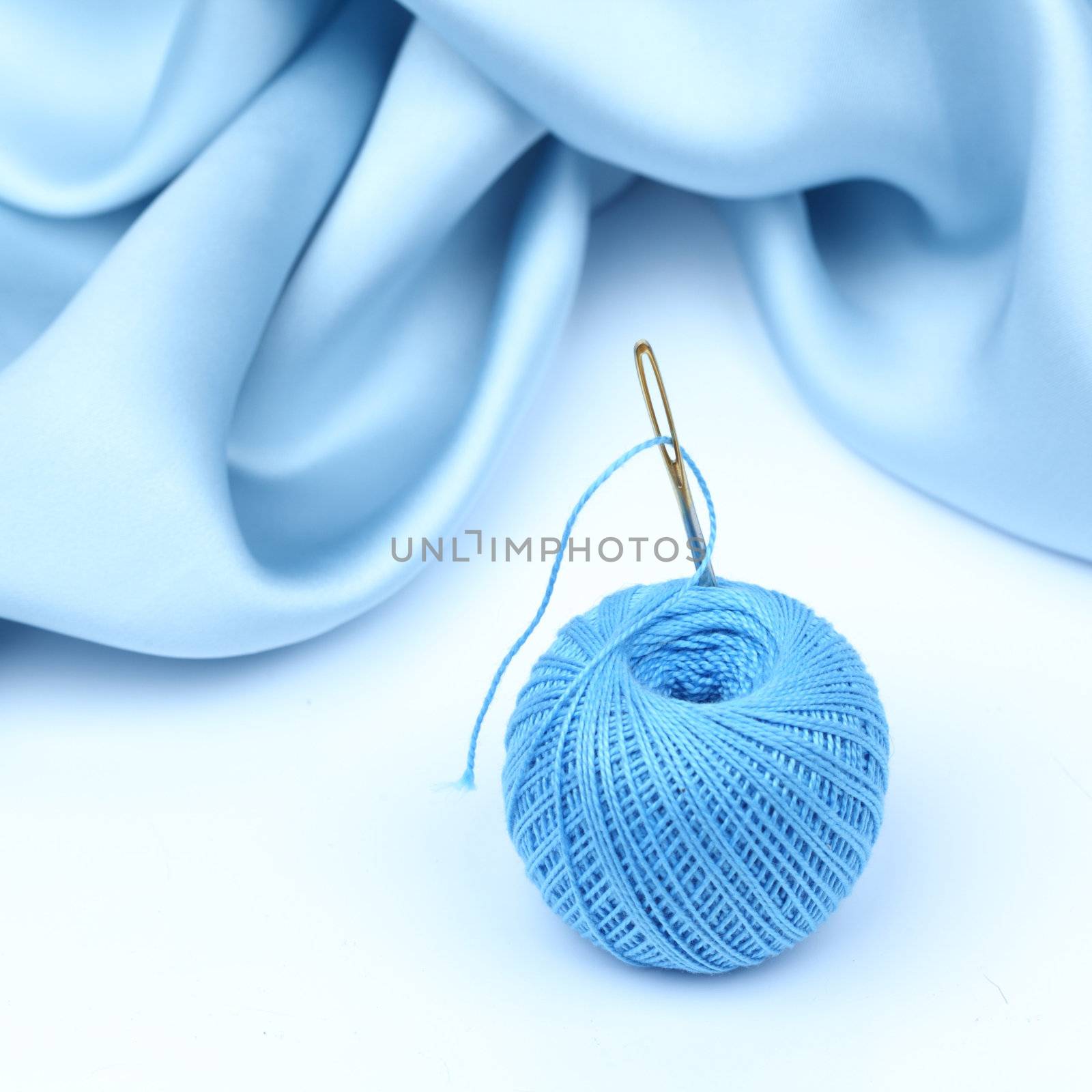 thread on blue silk isolated close up