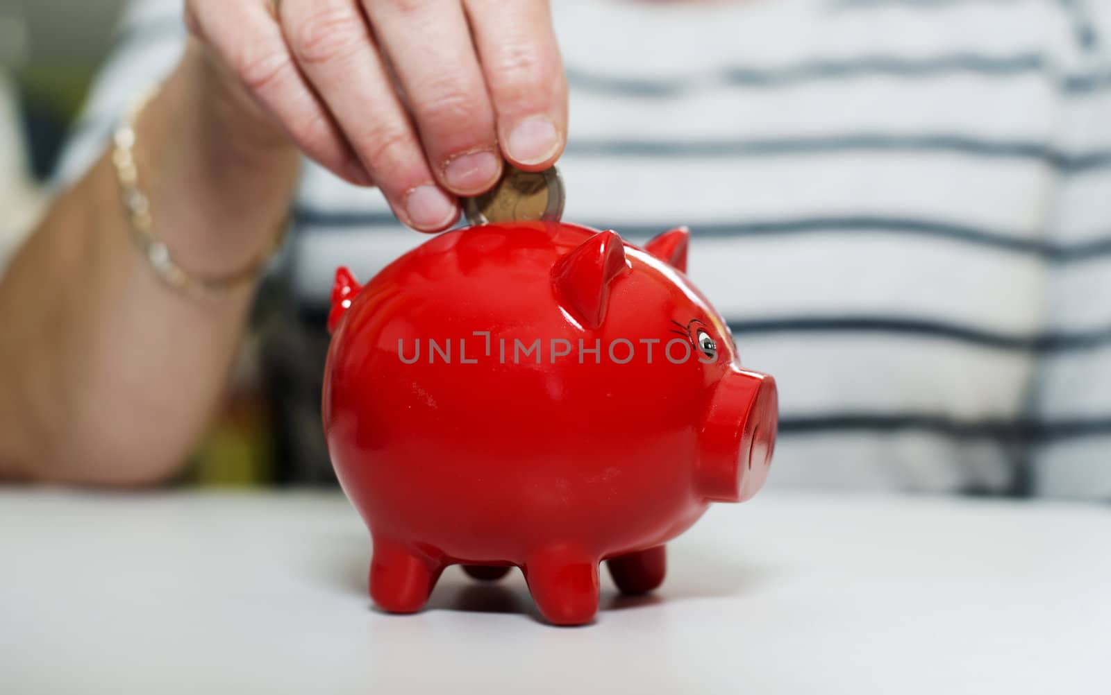 female hand putting euro in money pig