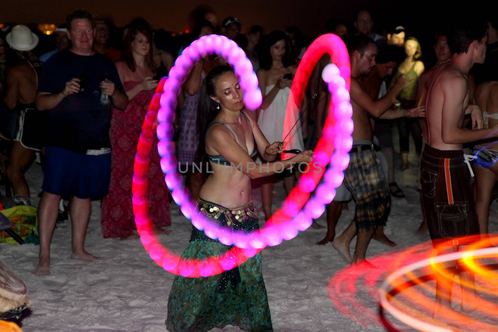 SIESTA KEY, FLORIDA - MAY 22: Dancers twirling colored perform in the center of a drum circle on Siesta Key Public Beach near Sarasota, Florida, May 22, 2011.  A slow shutter speed gives motion blur to the dancers colored lights and spectators as they move on the sand.