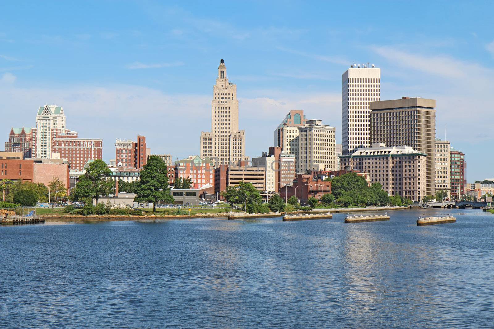 View of the skyline of Providence, Rhode Island, from the far side of the Providence River against a blue sky and white clouds
