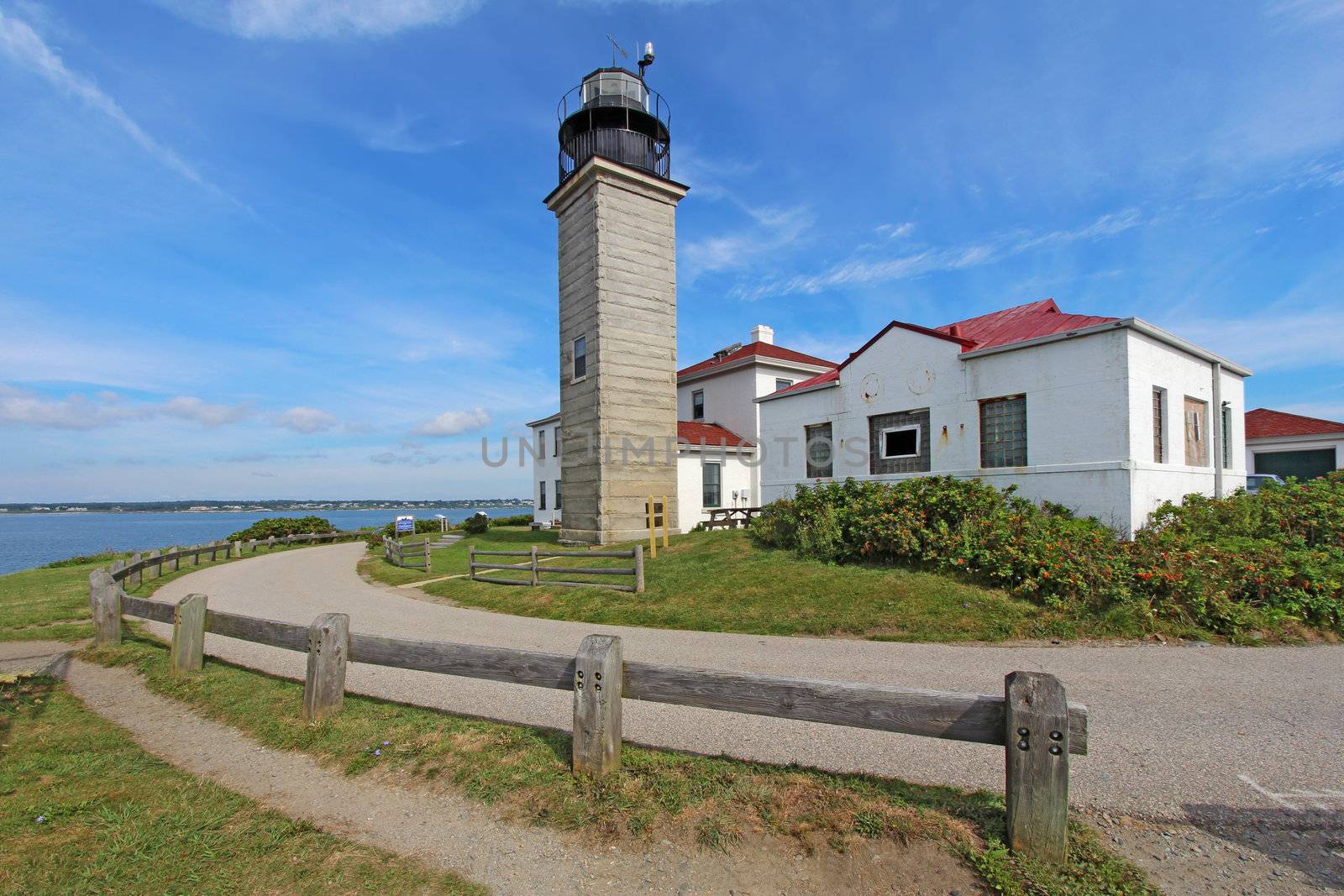 View of the Beavertail Light lighthouse near Jamestown on Conanicut Island, Rhode Island, with a bright blue sky and white clouds