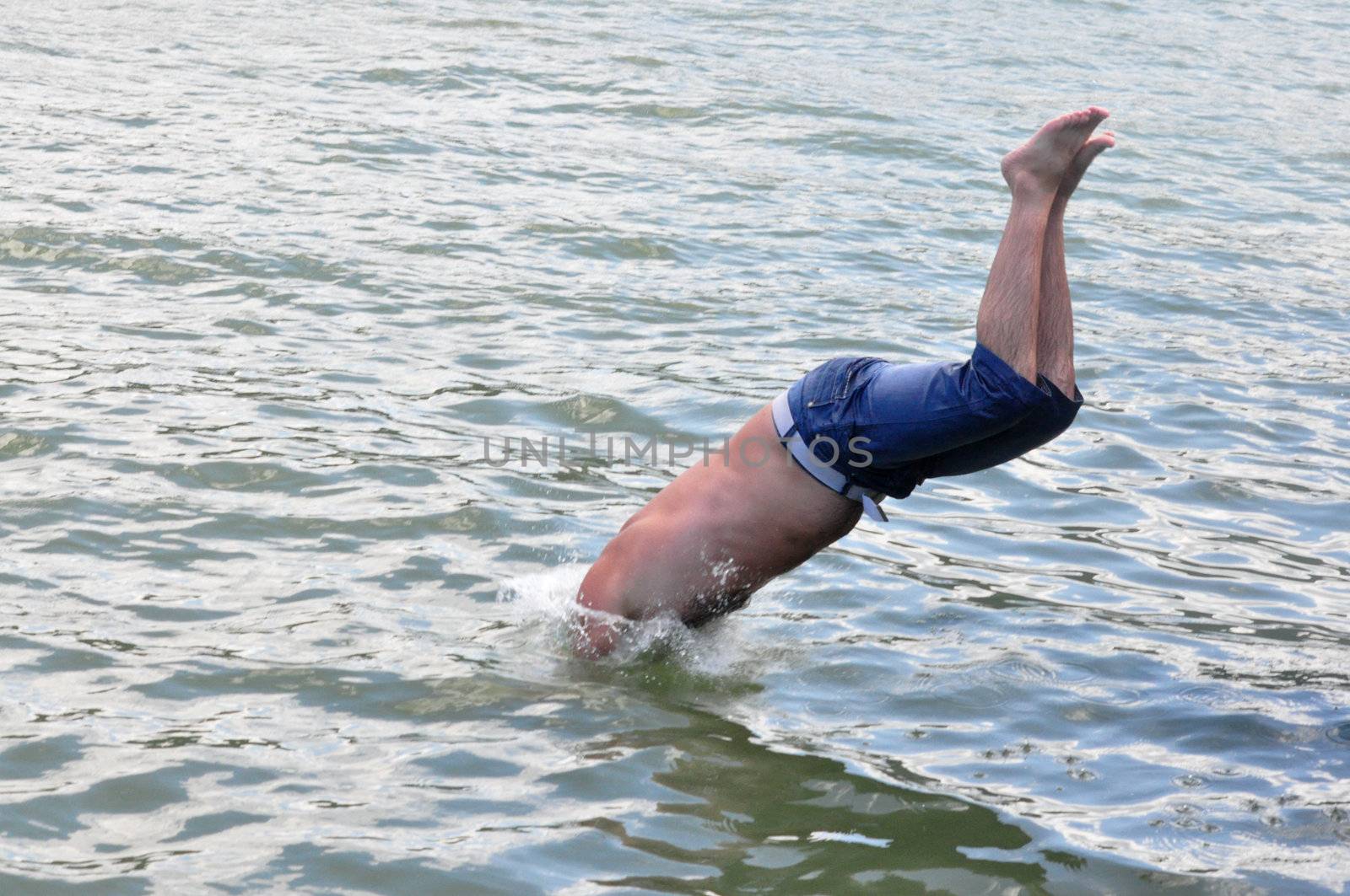 young man plunging into water in a summer day