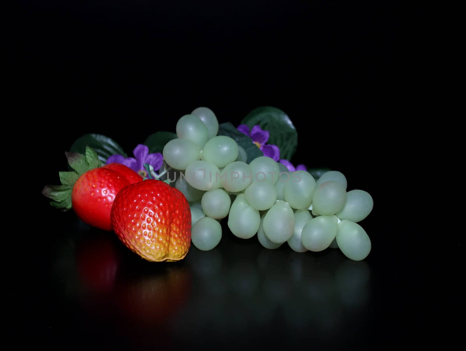 Bunch of grapes, strawberry and flowers over black