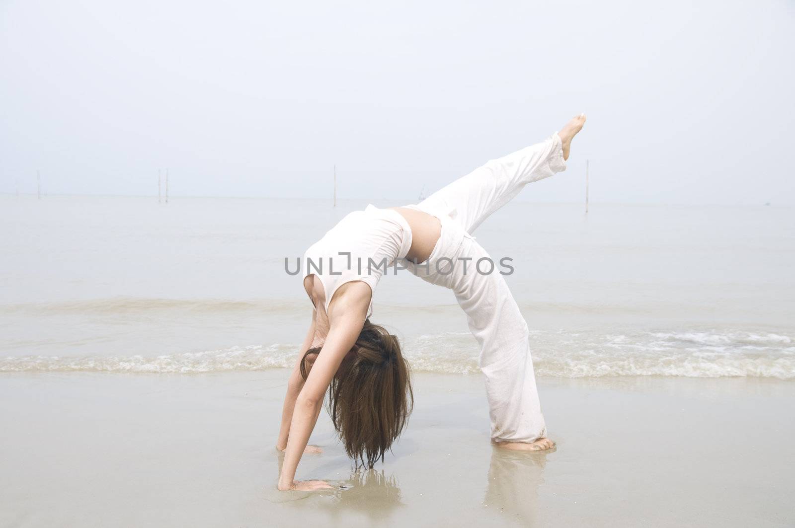 asian girl performing yoga on a beach