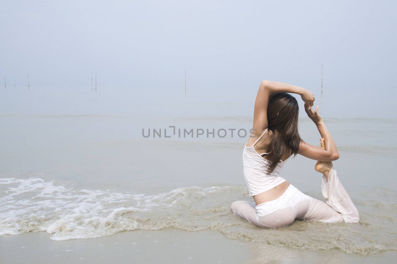 asian girl performing yoga on a beach