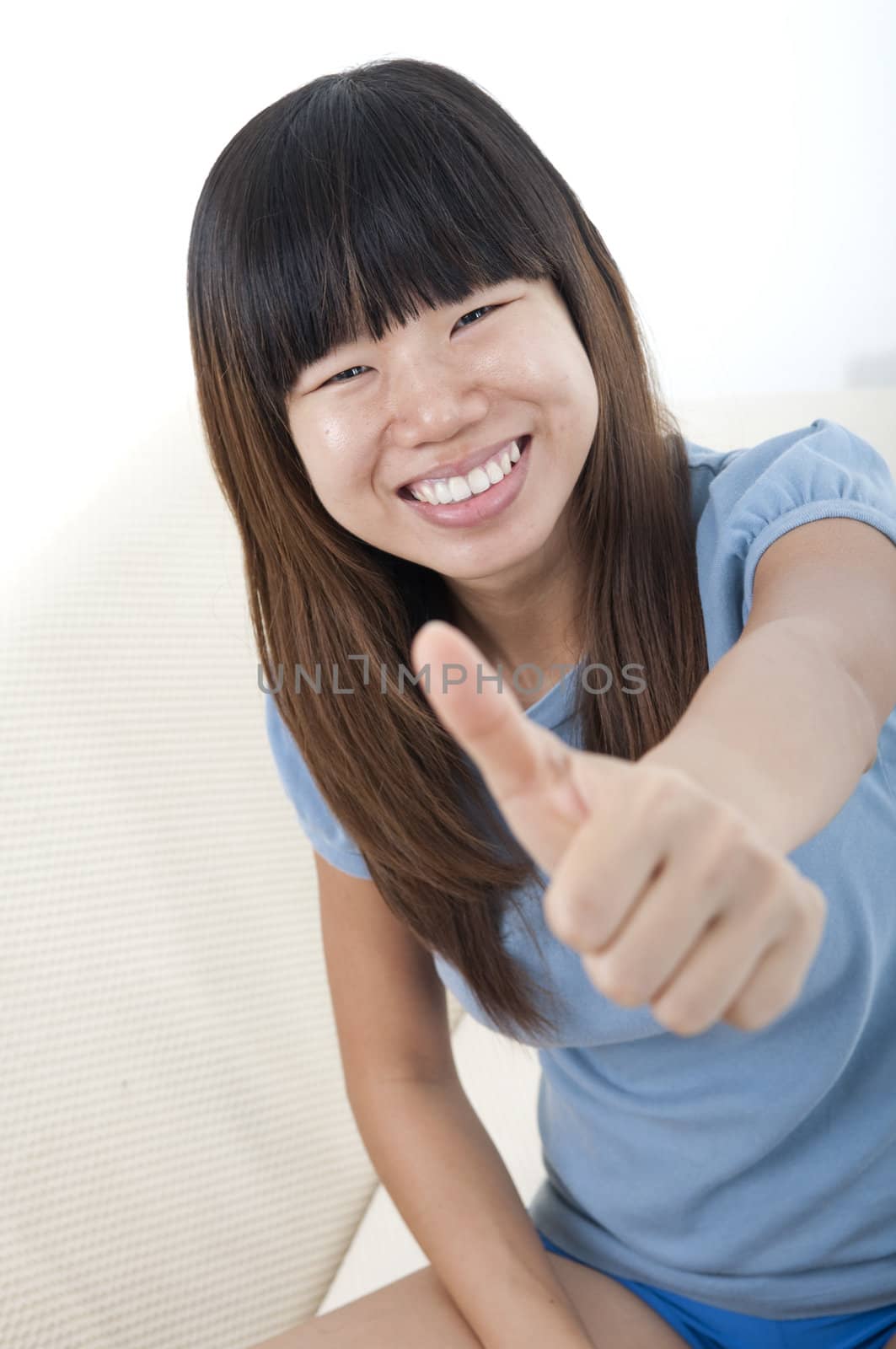 a happy asian girl giving a thumbs up 