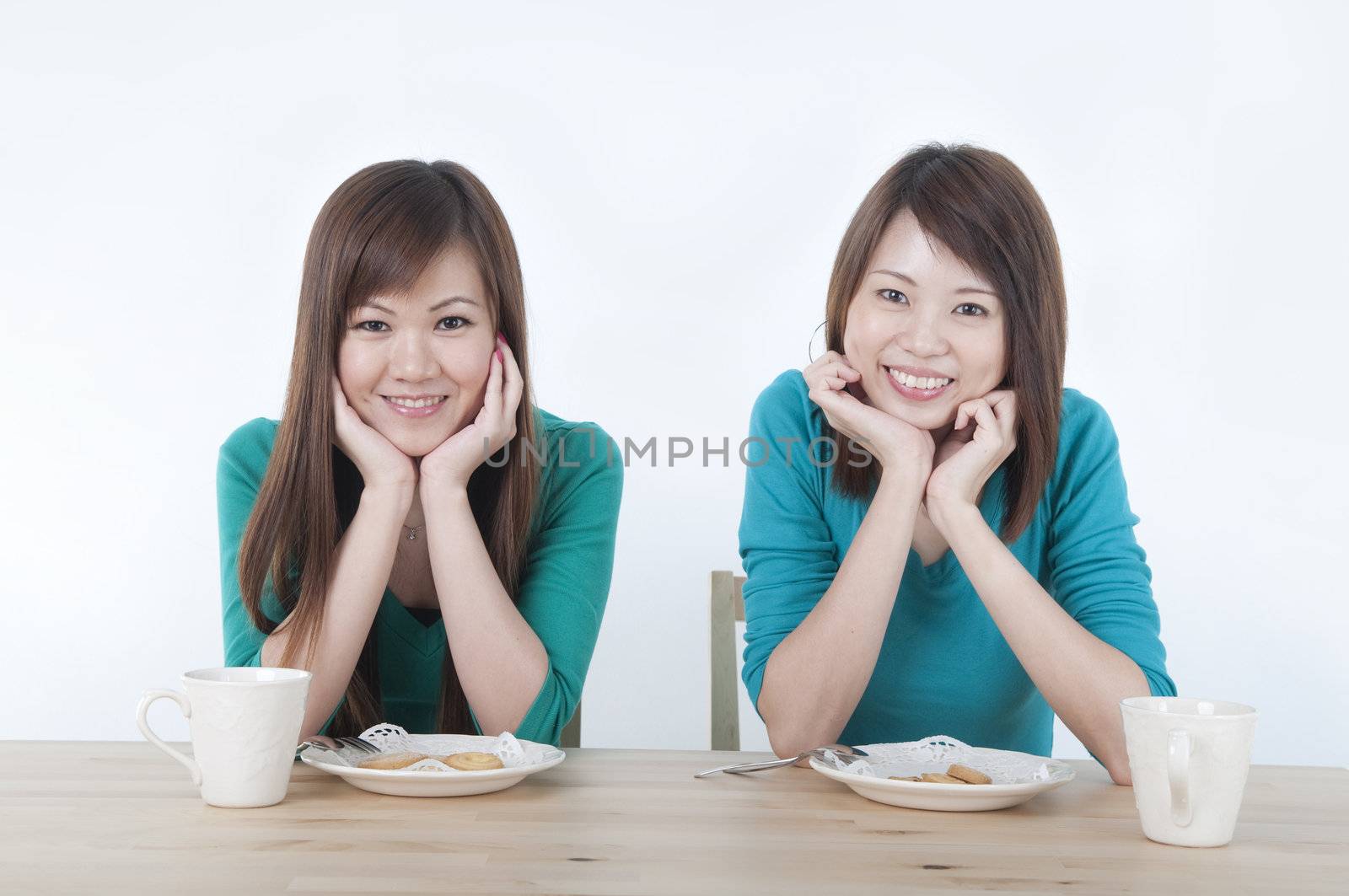 2 asian ethnic girls smieling while healthy eating