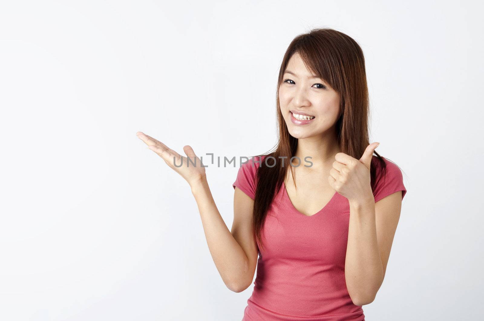 asian girl smiling with hand facing up and copyspace for advertising purpose