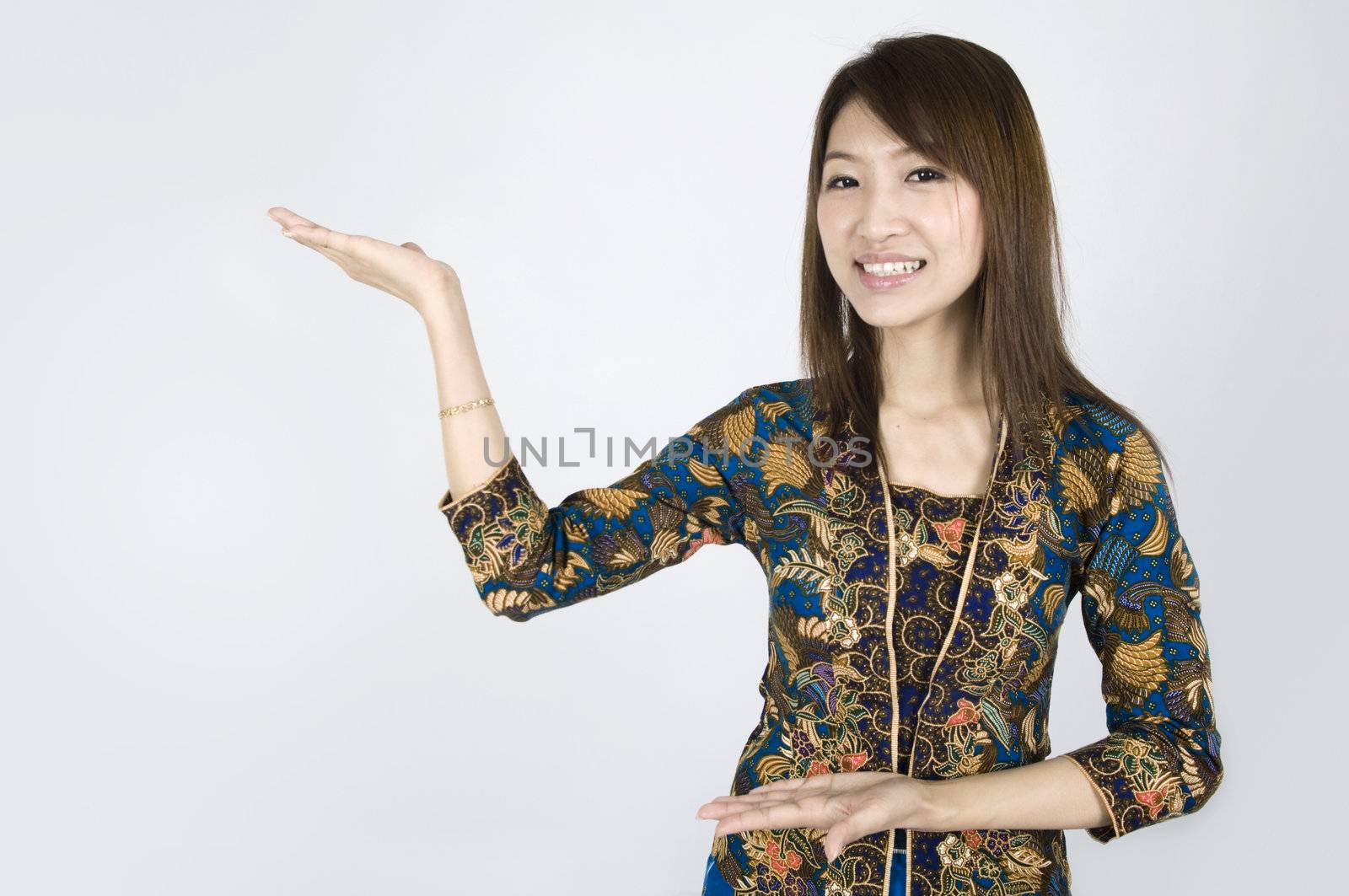 asian girl on a batik suit while posing a welcome sign