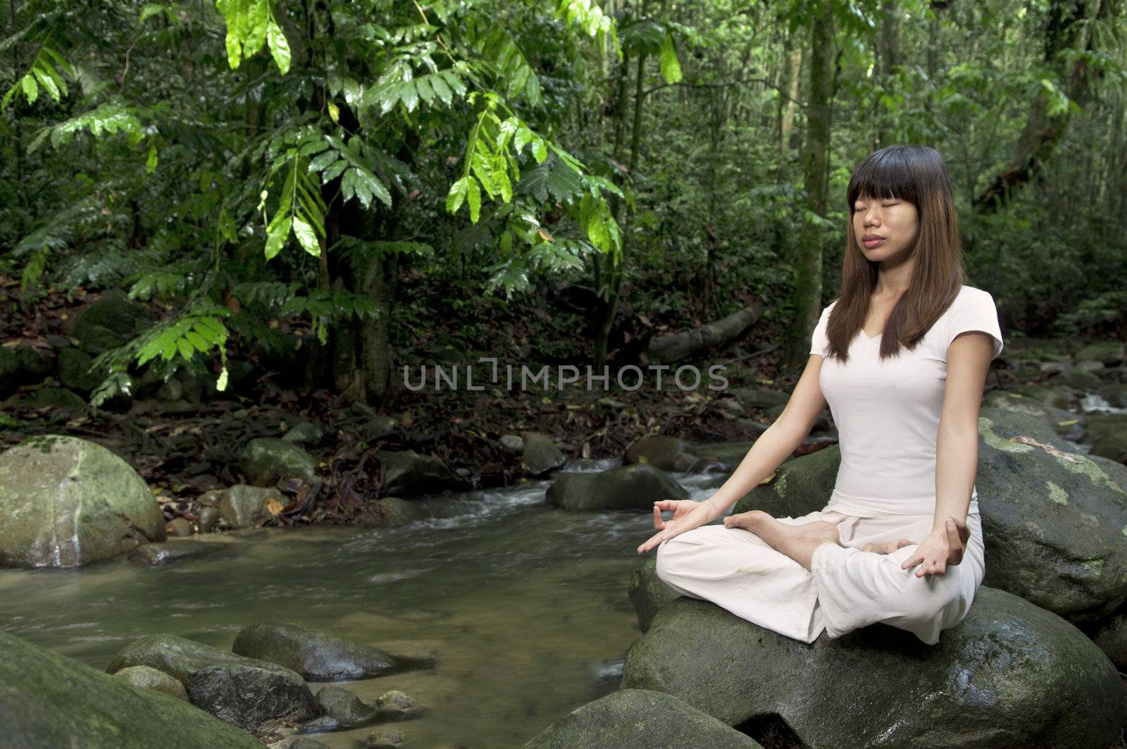 asian girl performing yoga with green forest background 