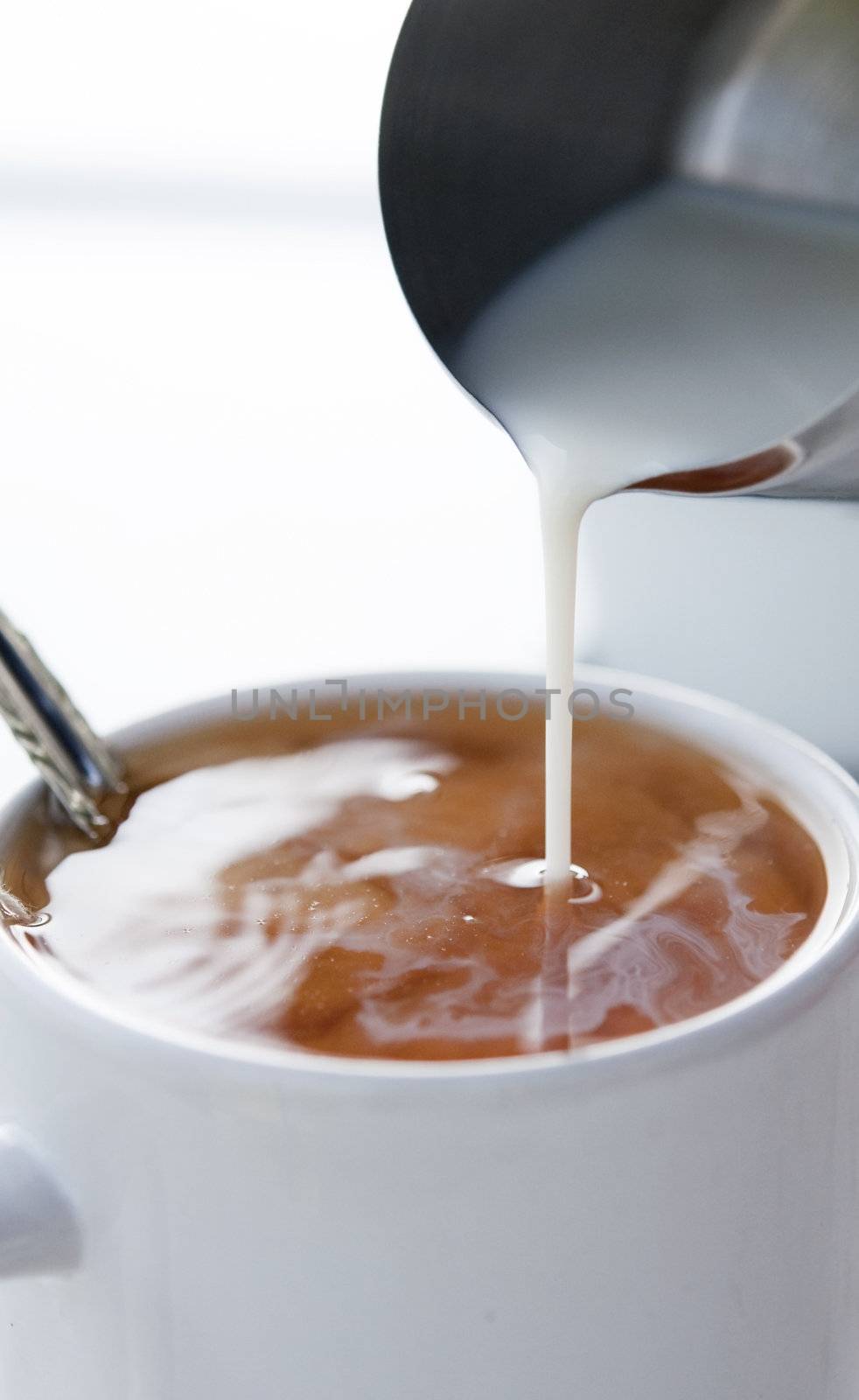  milk bring poured into a glass of tea 