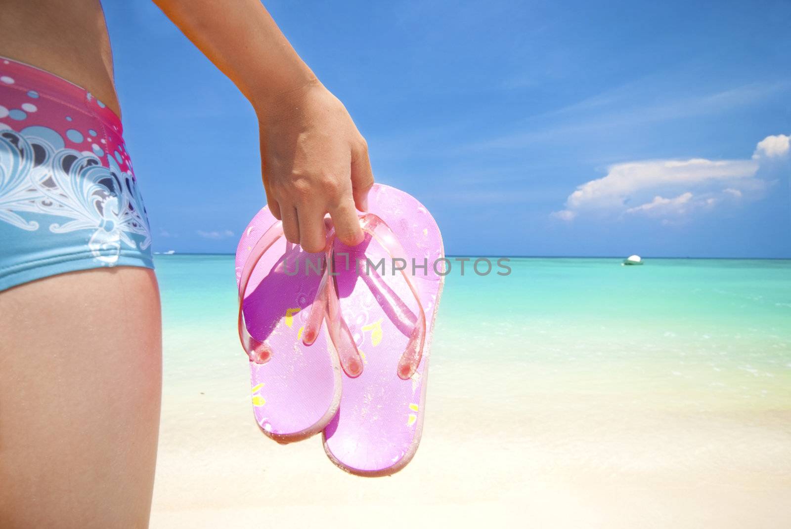 asian girl on a beach holding slipper with copyspace on right