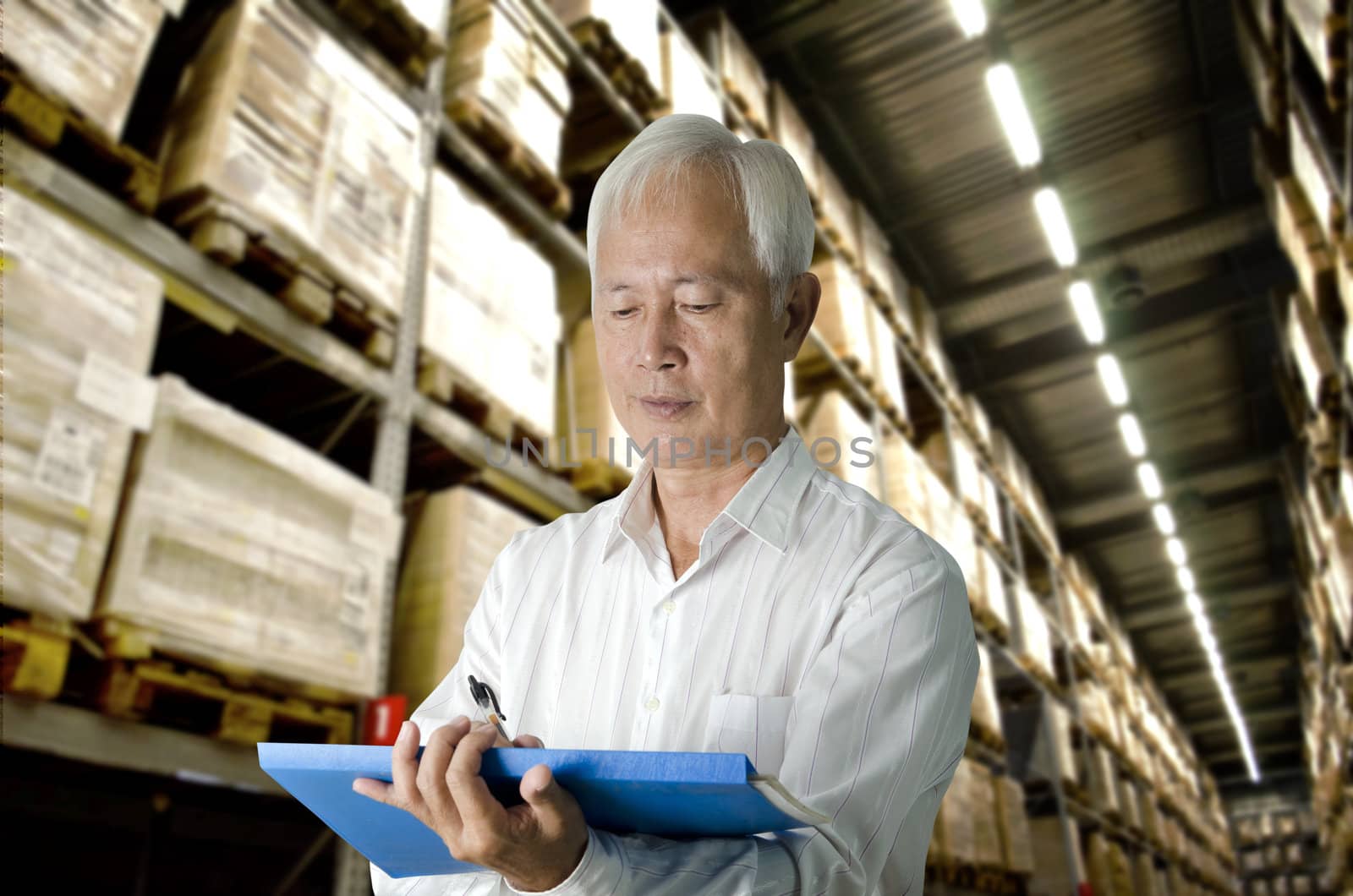 senior asian business man doing stock count in a warehouse