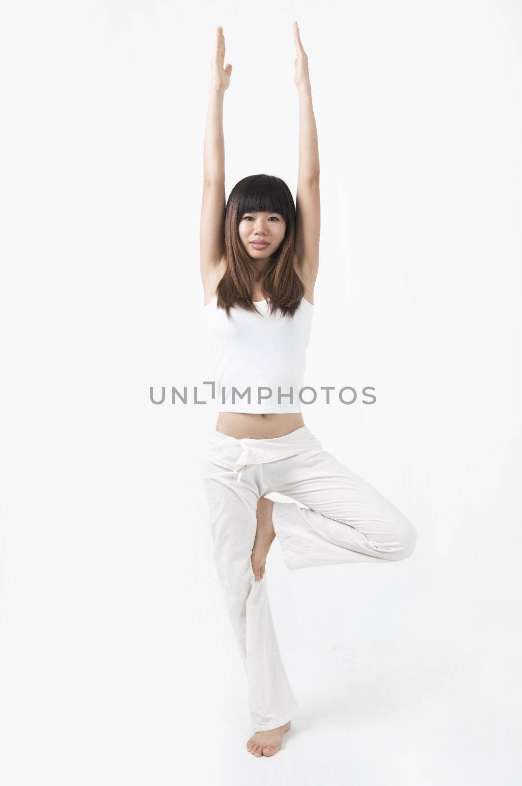 asian girl performing yoga  stand position with light background