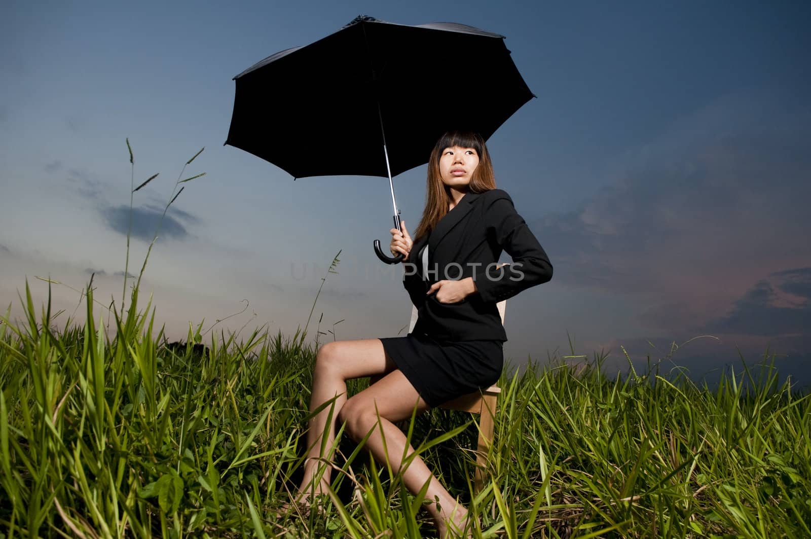 asian business women with an umbrella on a grass land 