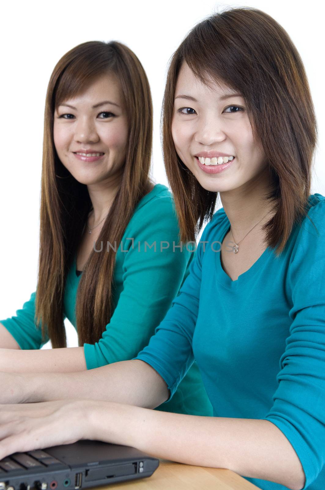 asian couple smiling while using a laptop 
