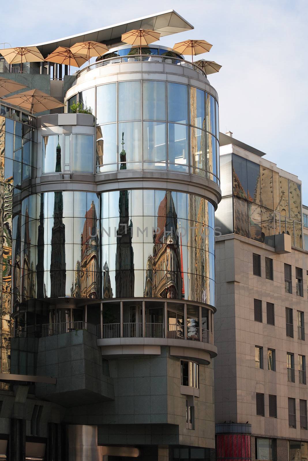 Nice glass modern building with cafe on roof. Reflection of old houses in big glass windows