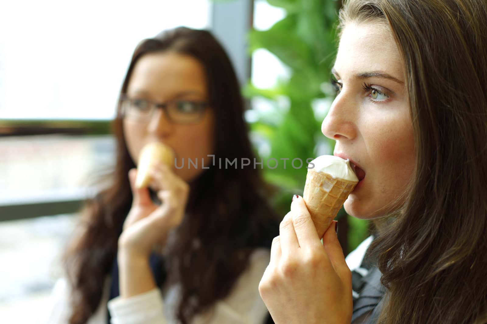 happy smiling women on foreground licking ice cream 