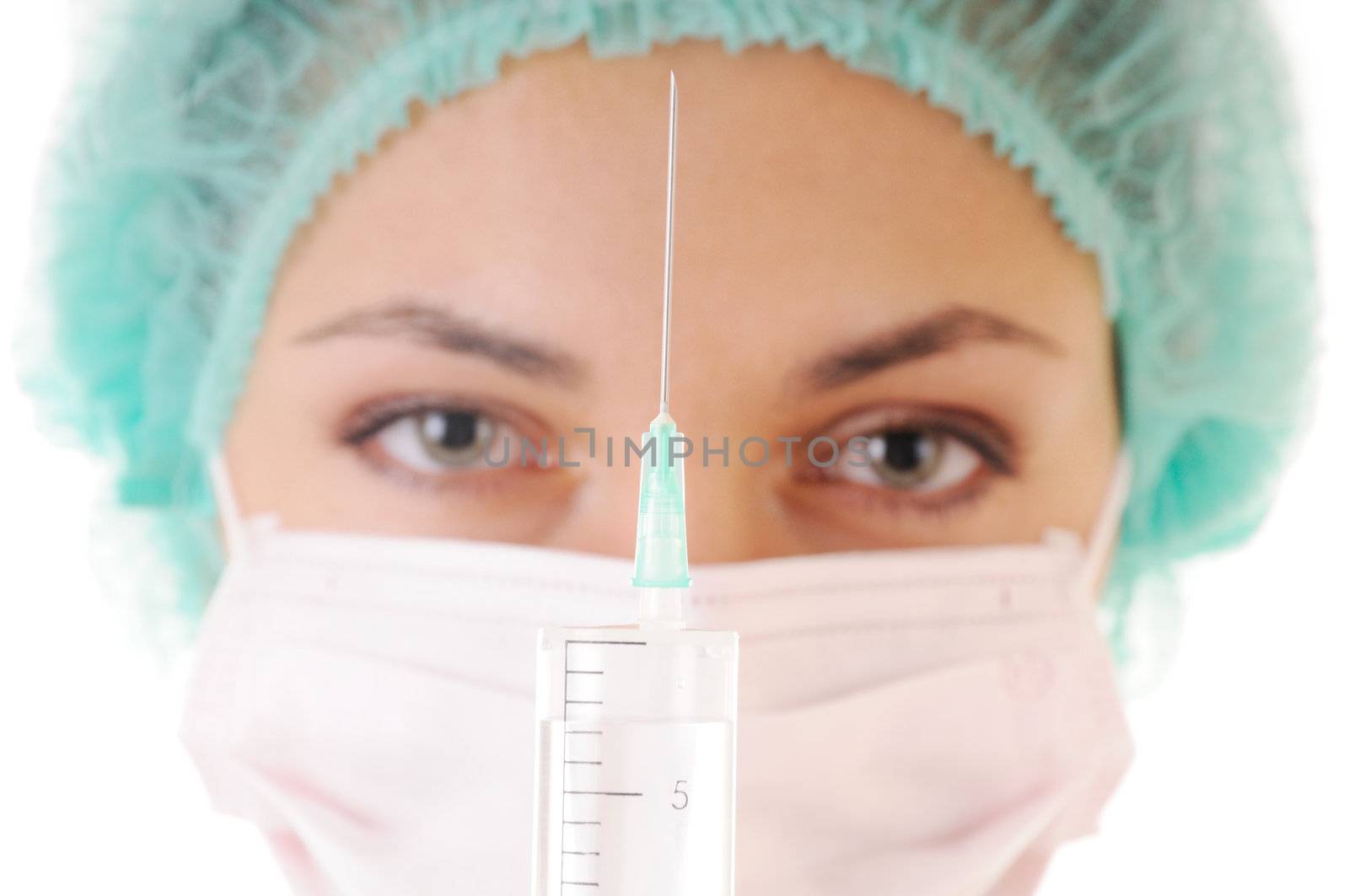 Syringe with solution for injection and woman in mask and cap on background. Focus on the syringe.