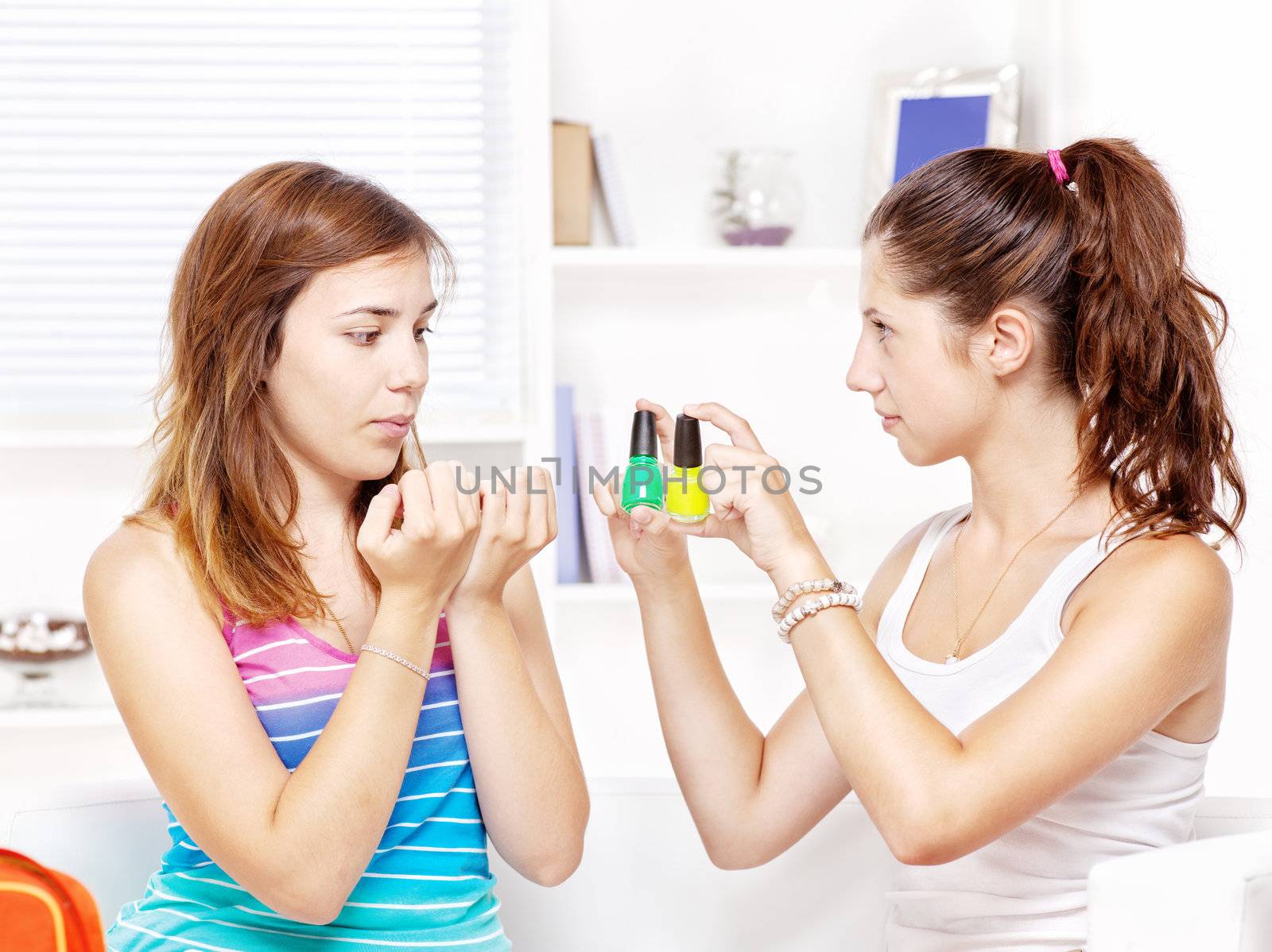 Two teenage girls polishing fingernails at her home