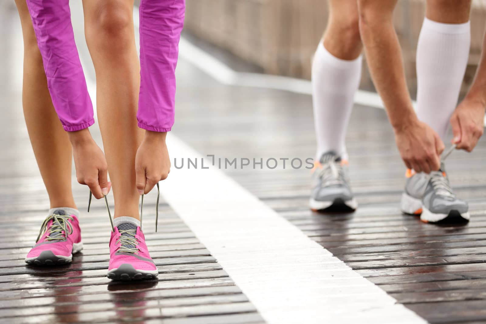 Runner feet. Running couple closeup of running shoes. Woman barefoot running shoes in foreground. Couple jogging on Brooklyn Bridge, New York.