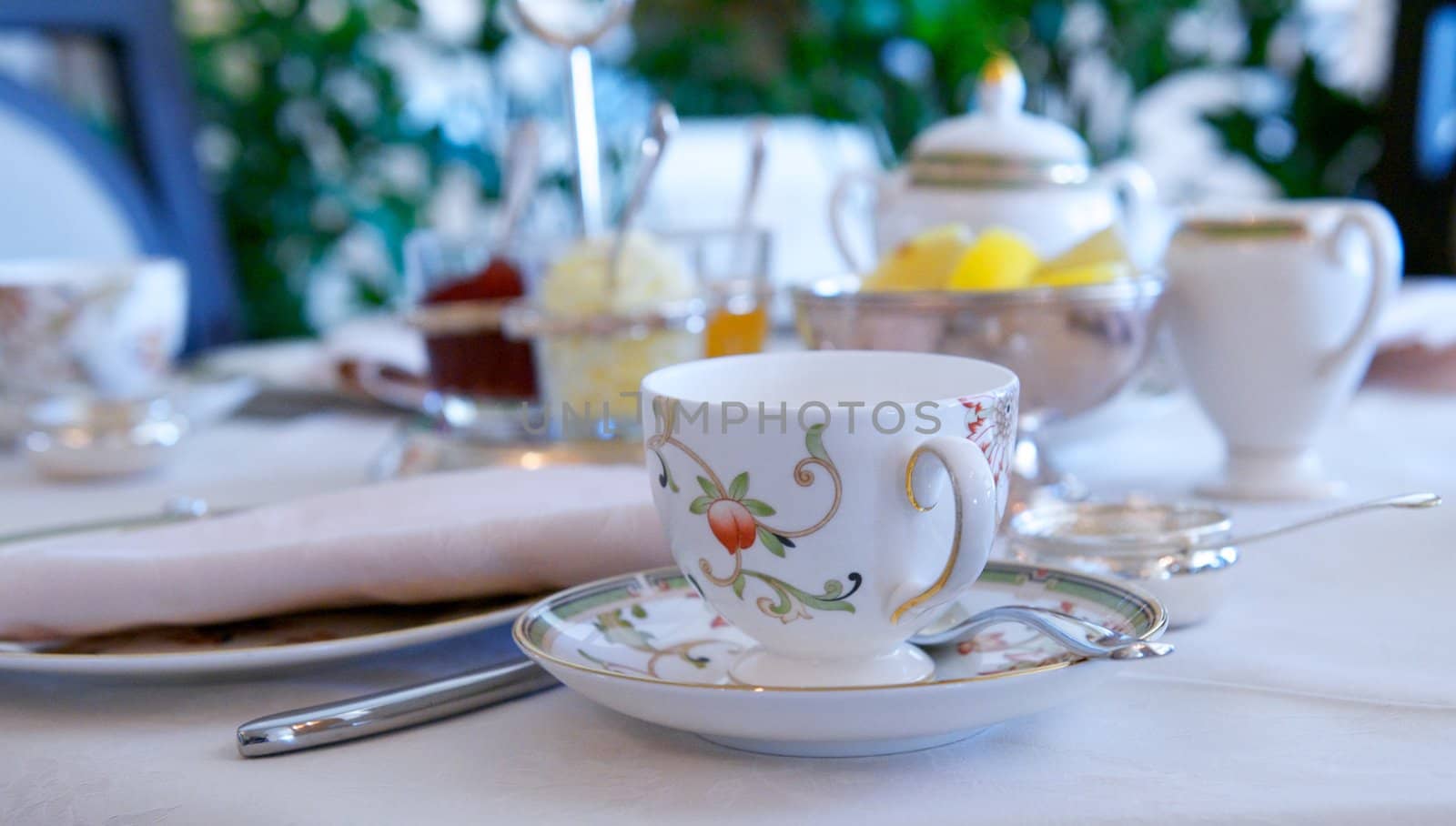 A delicately painted porcelain tea cup and saucer with a silver spoon