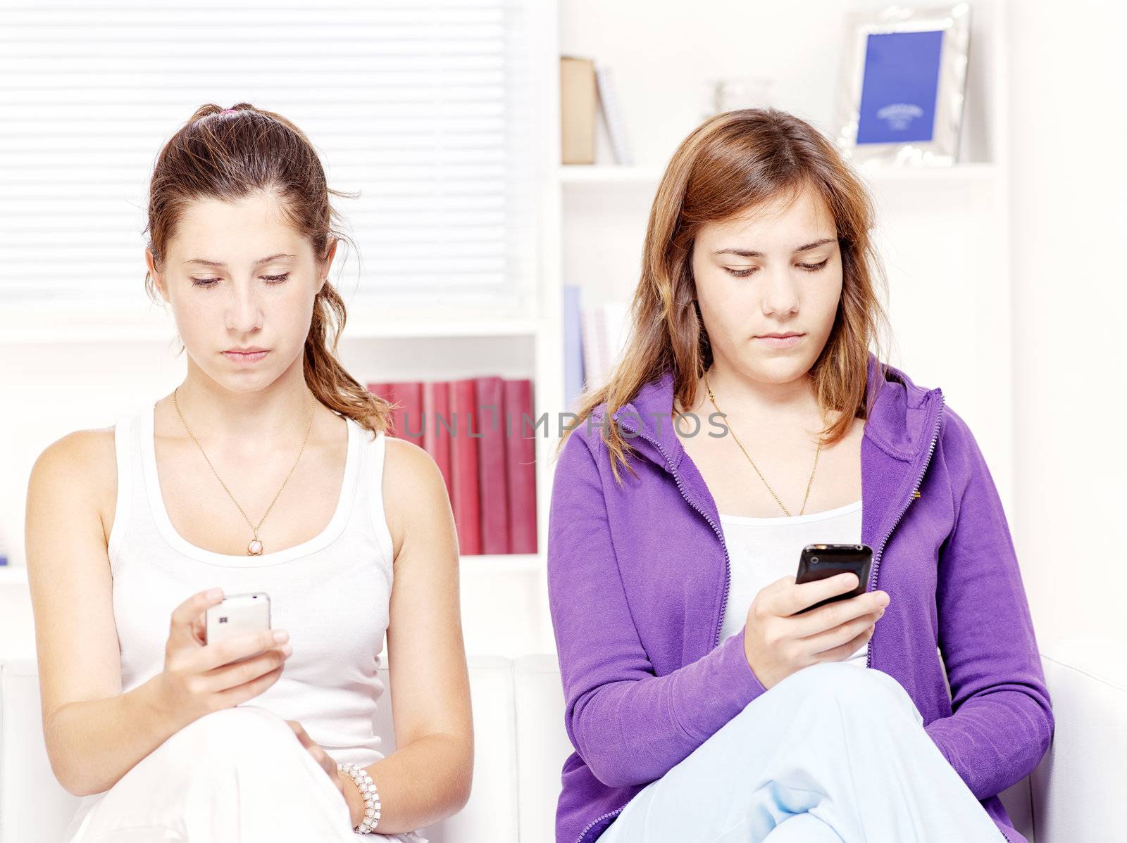 Two teenage girls sitting at home and sending messages