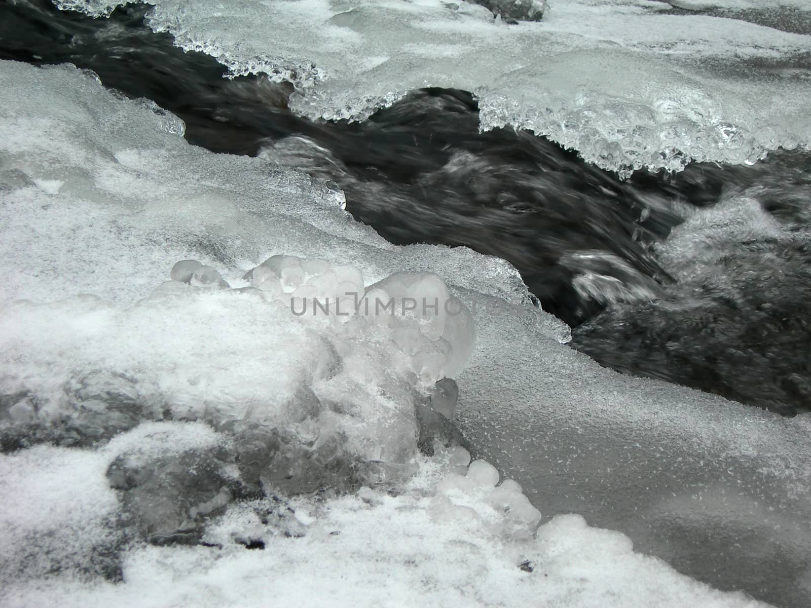              Brook is covered by ice and water flows under them with a small strem                  