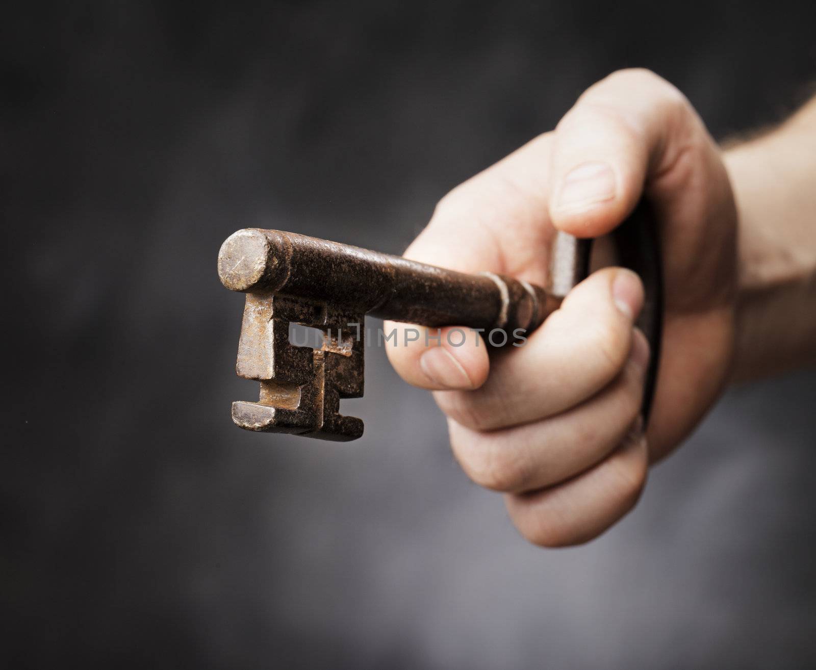 Man holding a big antique key in his hand. Very short depth-of-field.