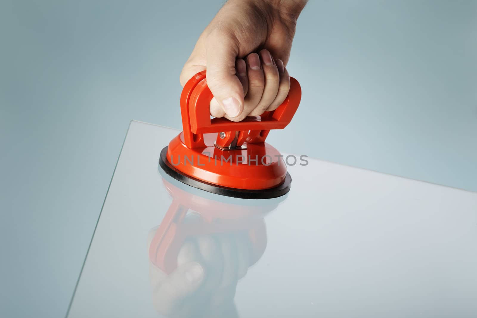 Man lifting a sheet of glass using a vacuum suction cup tool aka dent puller.