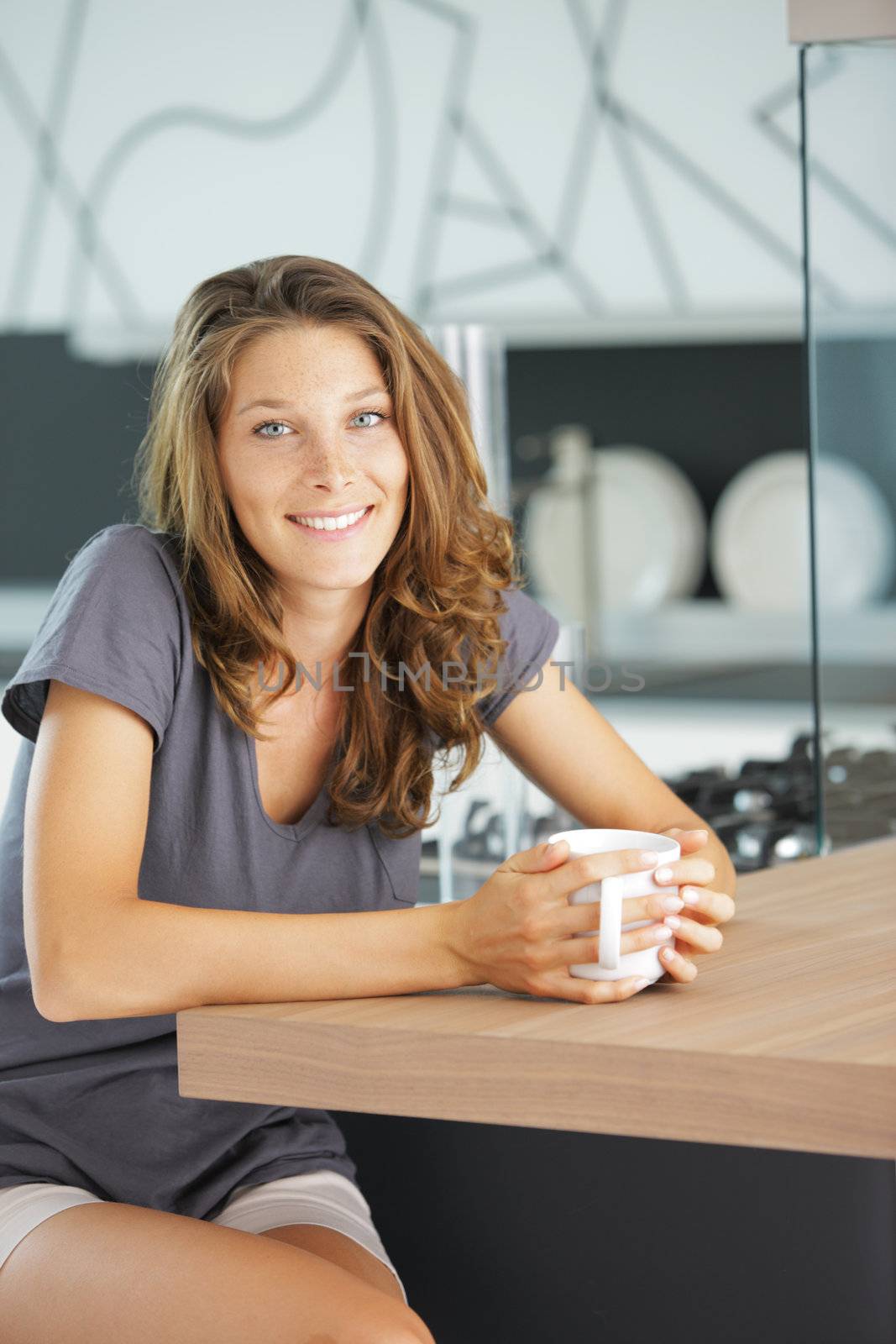 Beautiful girl in kitchen with a cup of cofee or tea