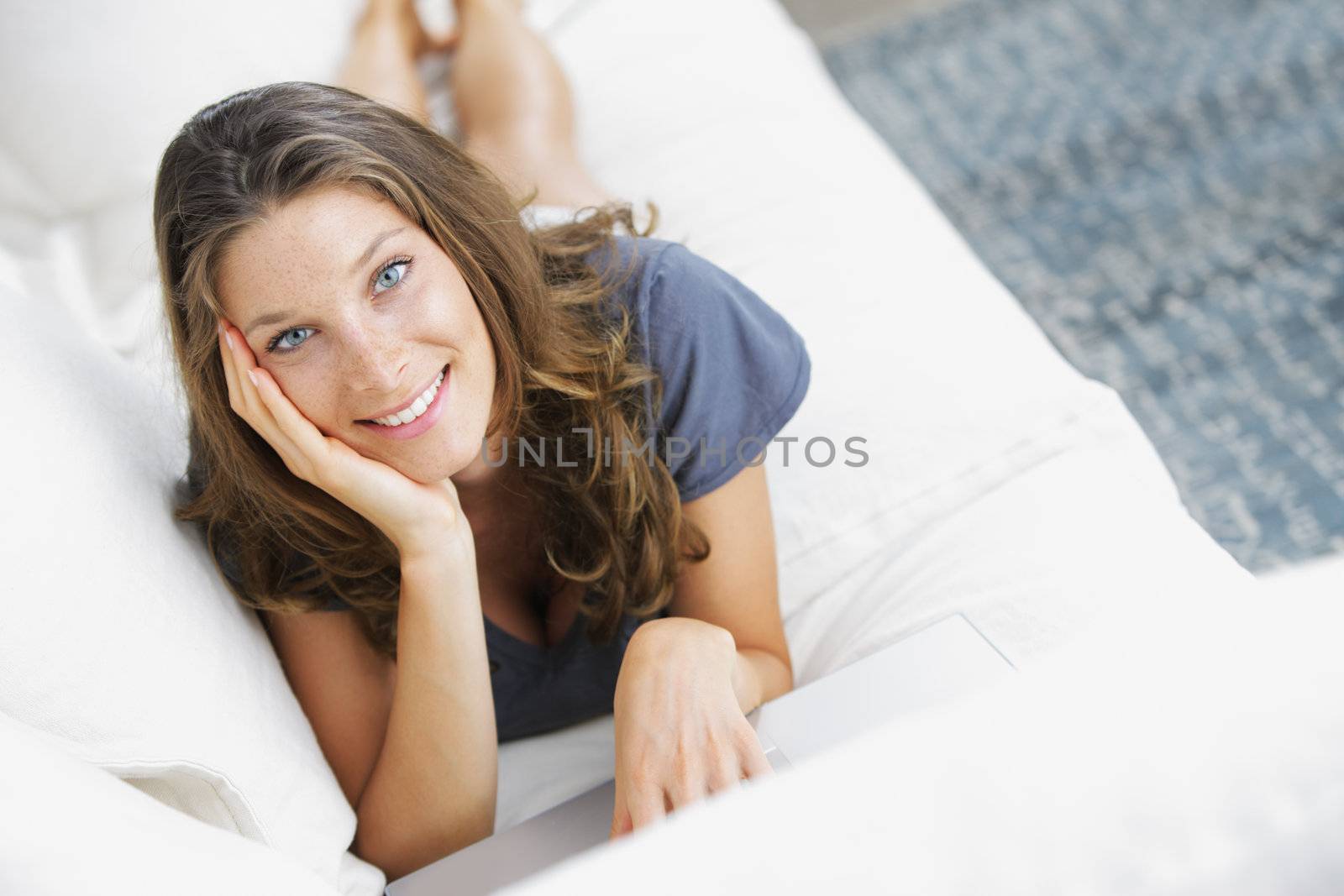 Pretty woman lying on sofa with laptop