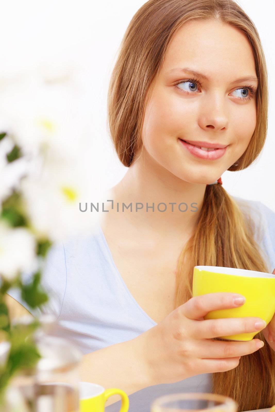 Beautiful young woman drinking tea from yellow cup